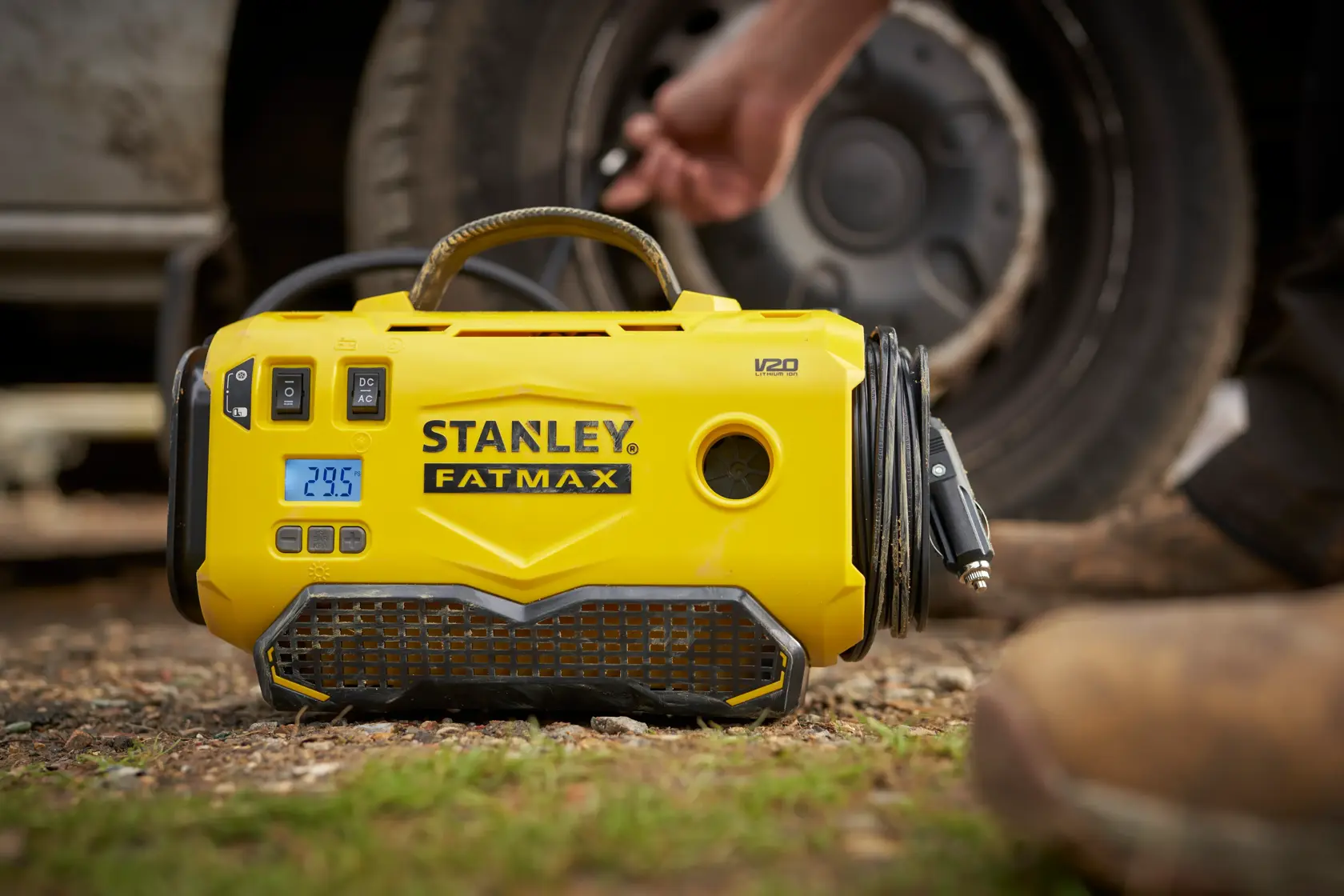 STANLEY SFMCE520B gelber, tragbarer Reifenfüller mit Digitalanzeige, draußen neben einem Autoreifen.