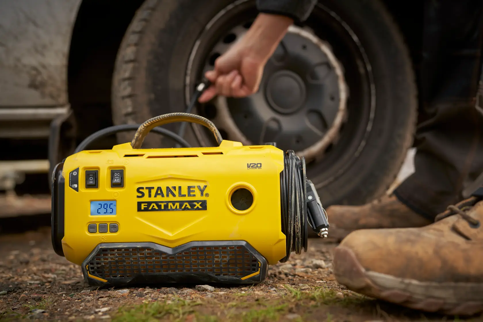 STANLEY SFMCE520B tragbarer gelber Reifenfüller im Einsatz neben einem Fahrzeugrad im Freien.