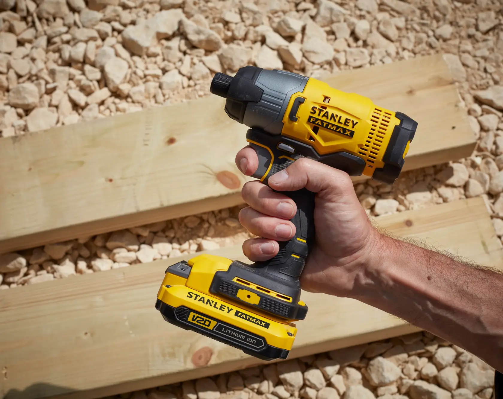 Foto eines STANLEY SFMCF800C2K kabellosen Schlagschraubers, gelb und schwarz, in der Hand auf Holz.