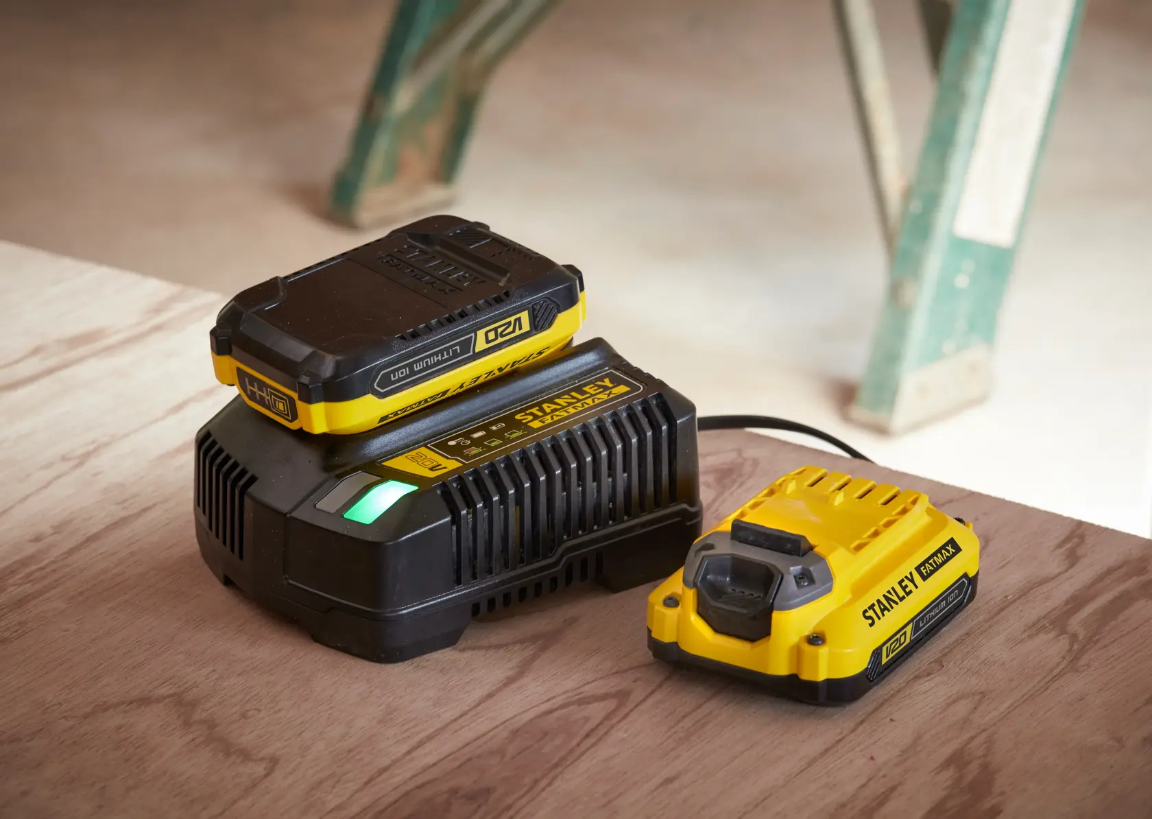 STANLEY SFMCF800C2K Fotografie von gelbem und schwarzem Batterieladegerät und Batterie auf Holzoberfläche