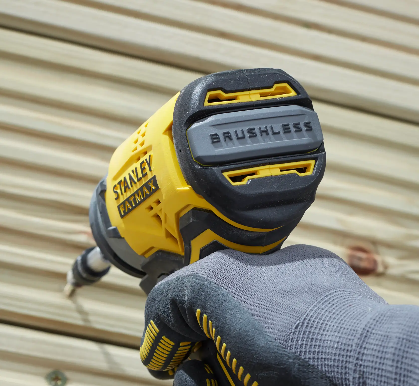 STANLEY SFMCF810B bürstenloser Schlagschrauber in behandschuhter Hand, Nahaufnahme im Freien.