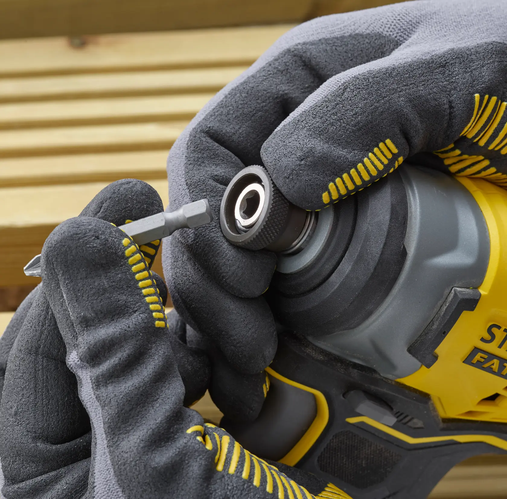 Foto des STANLEY SFMCF810B Schlagschraubers in Nahaufnahme, behandschuhte Hände setzen einen Bit ein.