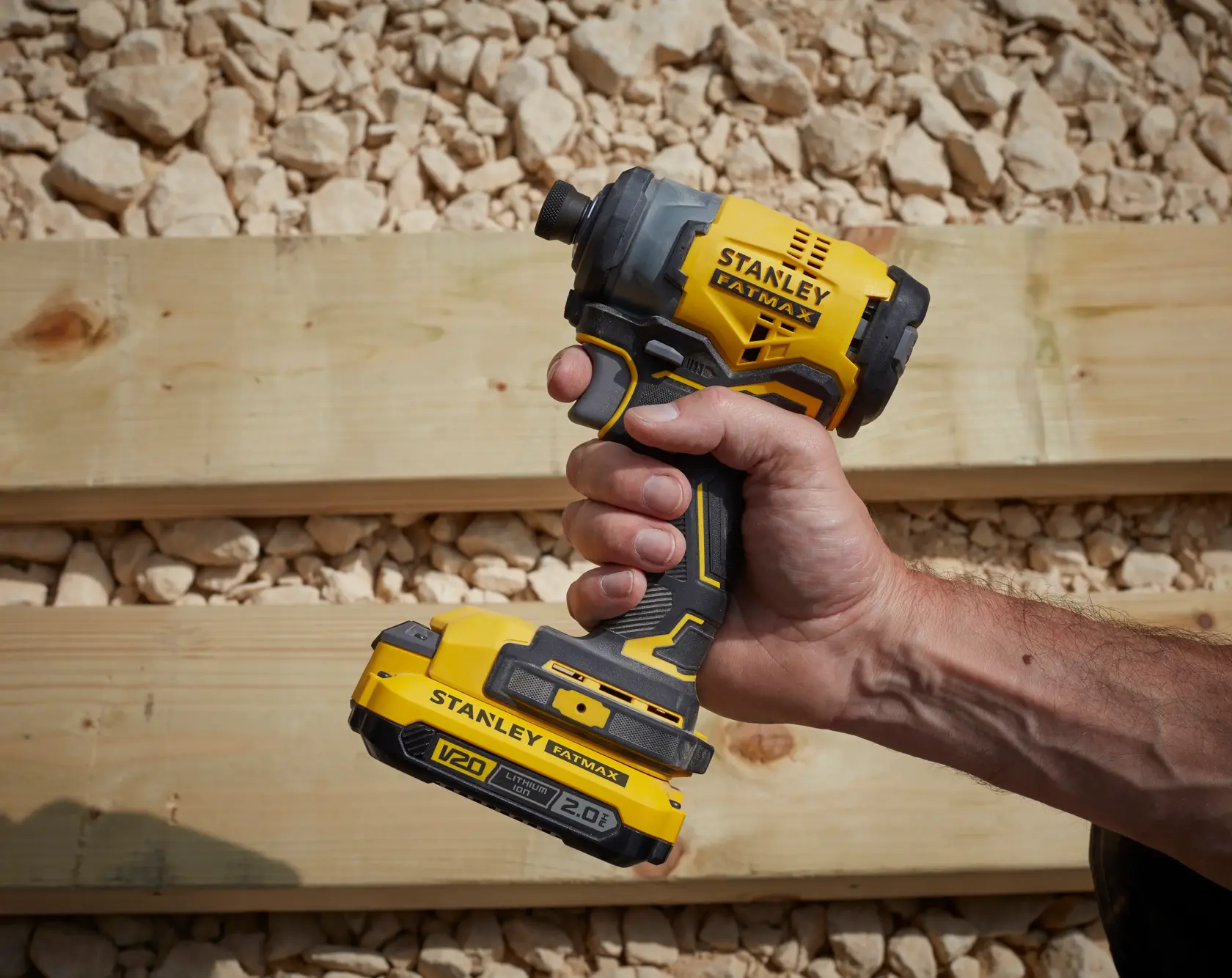 STANLEY SFMCF820D2K V20 kabelloser Schlagschrauber gelb-schwarz in der Hand gehalten, draußen.