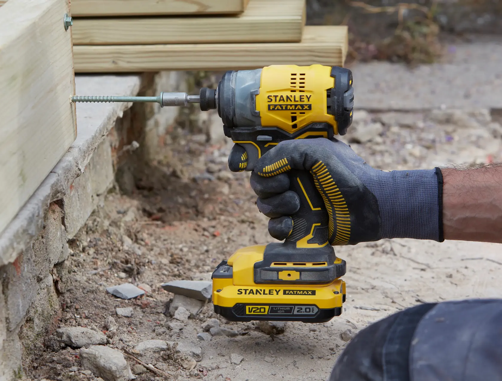 Foto des kabellosen Schlagschraubers STANLEY SFMCF820D2K, gelb und schwarz, schraubt in Holz.