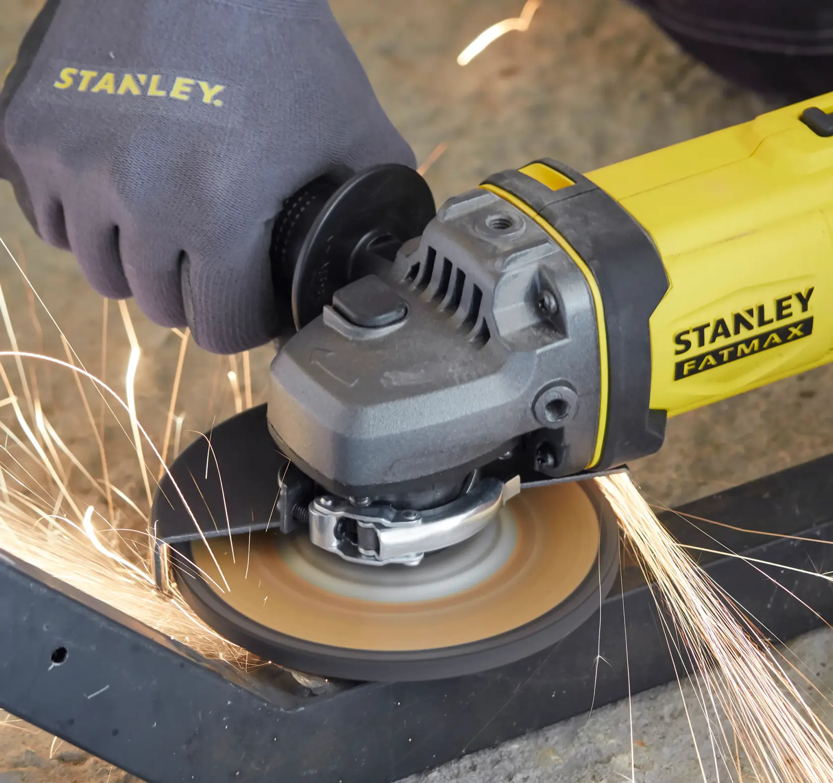 STANLEY SFMCG400B Winkelschleifer schneidet Metall, gelb und schwarz, Funken fliegen, Nahaufnahme.