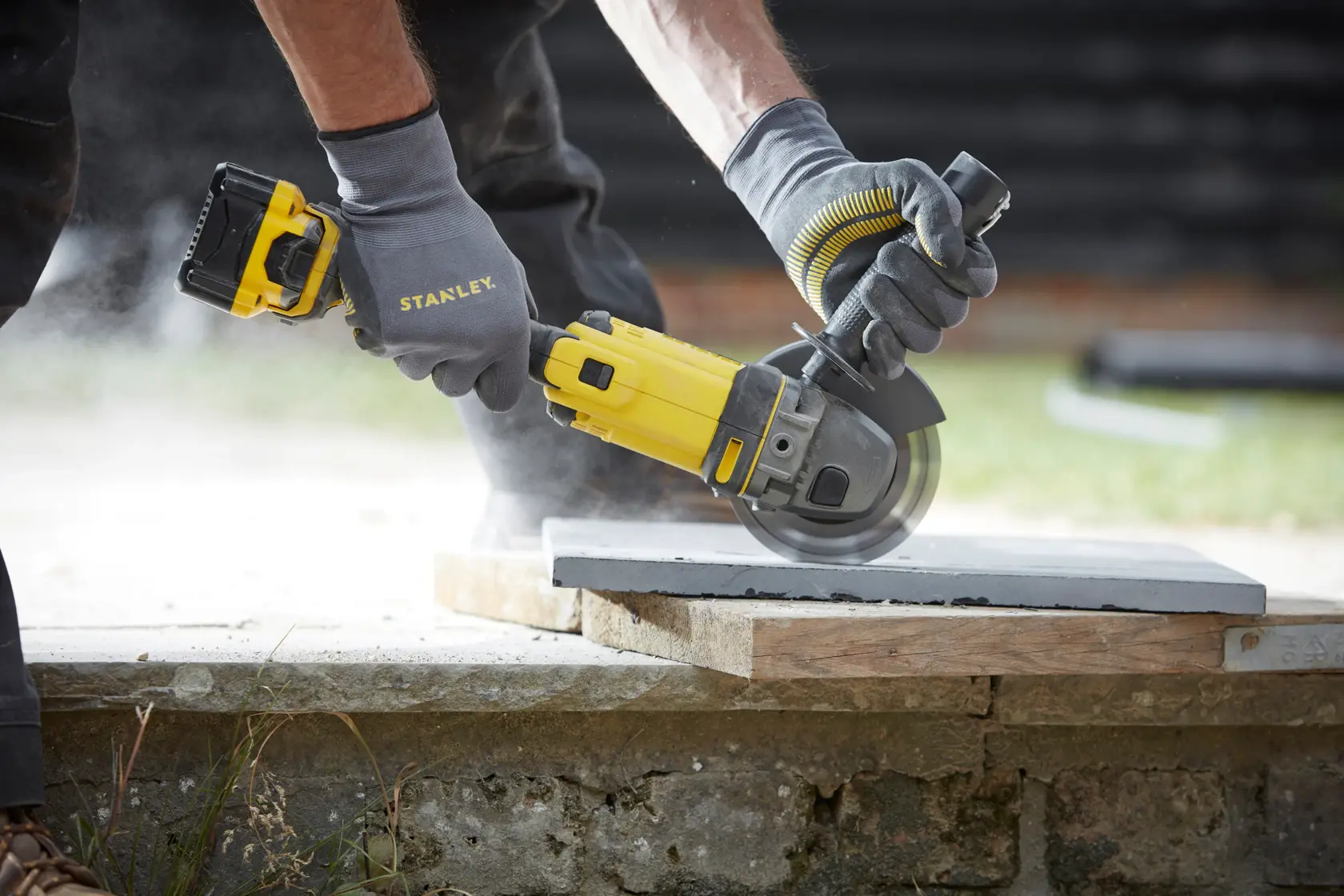STANLEY SFMCG400M2K Akku-Winkelschleifer beim Schneiden von Beton, Nahaufnahme im Freien.