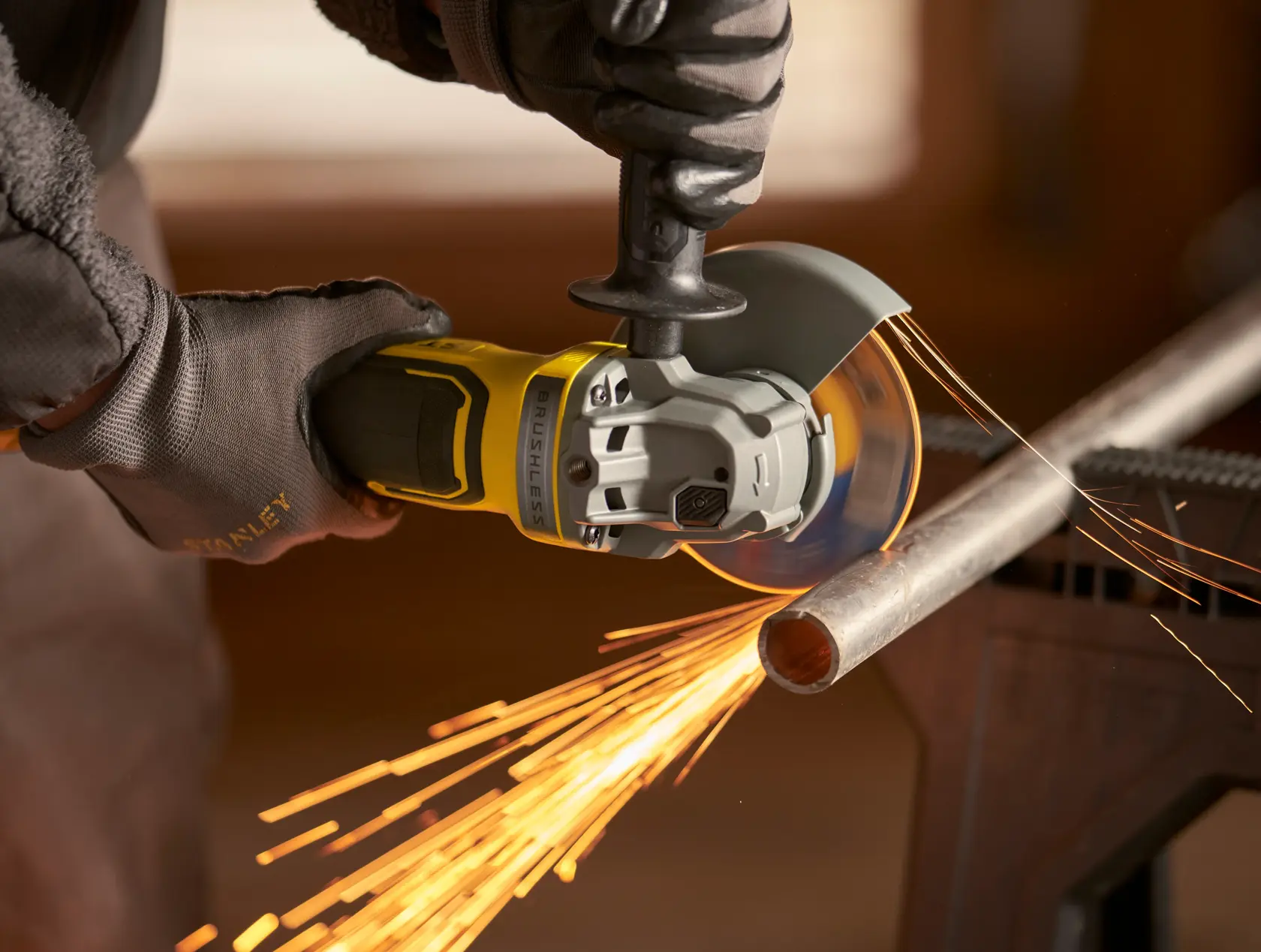 Stanley SFMCG700M2K Schleifer schneidet Metallrohr mit Funken, Nahaufnahme.