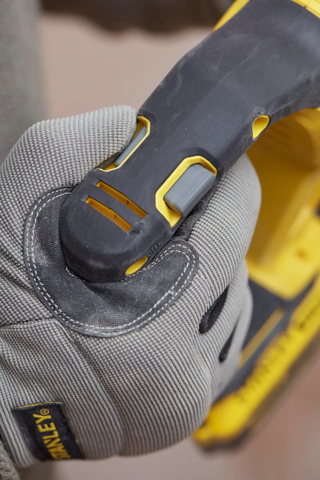 STANLEY SFMCH900B Elektrowerkzeug-Griff von behandschuhter Hand gehalten, Nahaufnahme Fotografie.