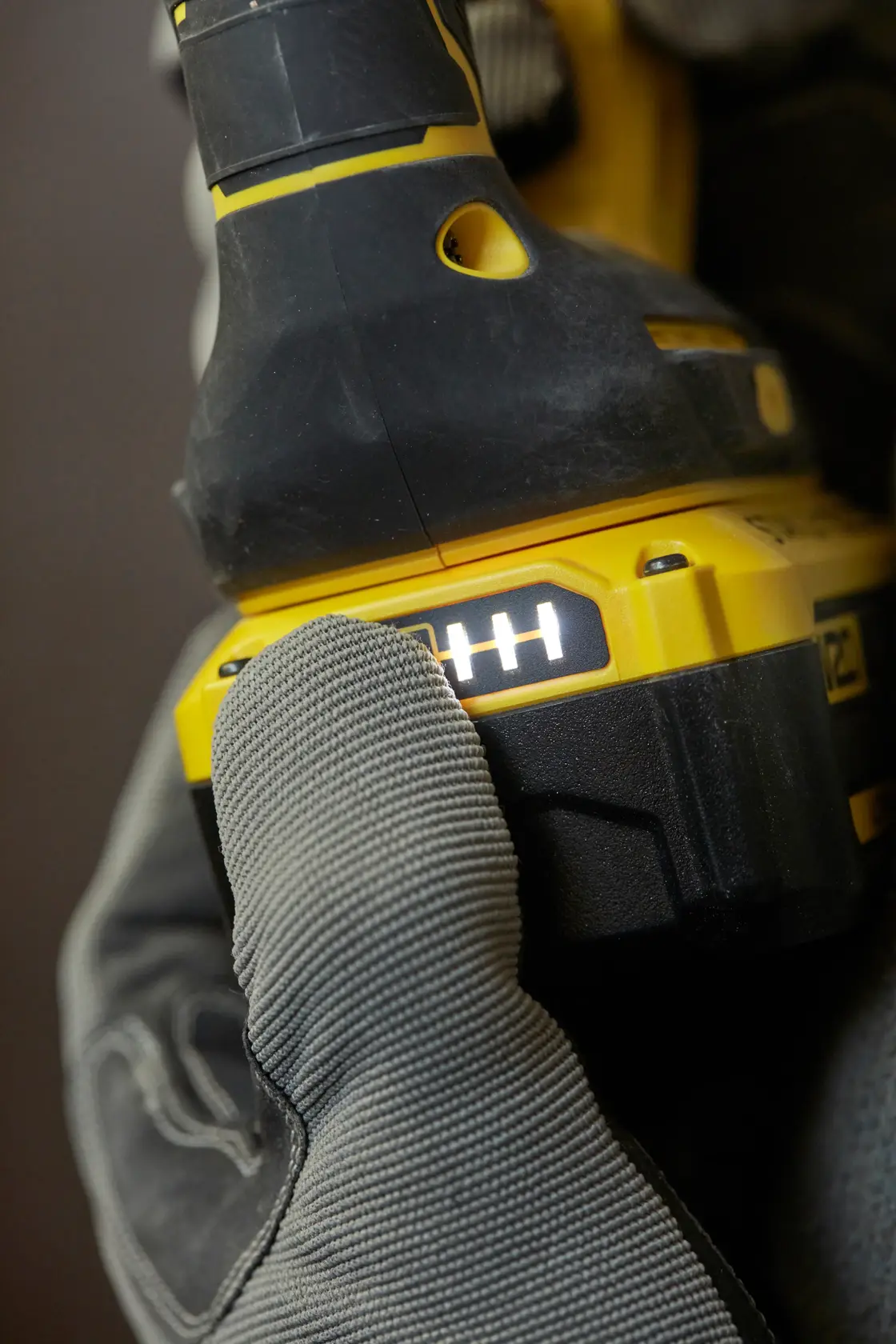 STANLEY SFMCH900M22 Akku-Bohrer Energieanzeige in Nahaufnahme, gehalten von behandschuhter Hand, Seitenansicht.