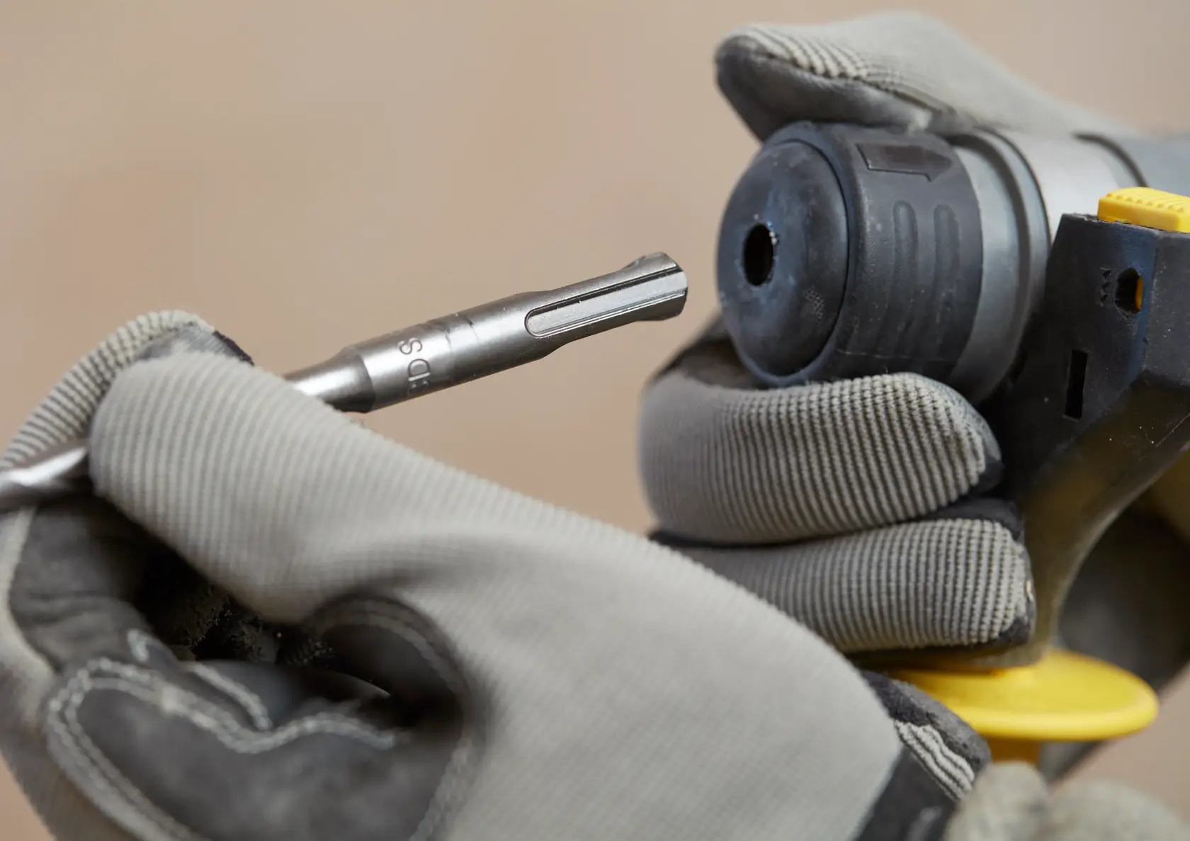 STANLEY SFMCH900M22 Drehhammer Nahaufnahme mit behandschuhter Hand beim Einsetzen eines Bohrers, Produktfoto.
