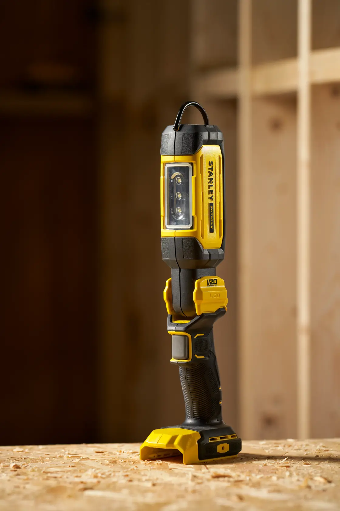 STANLEY SFMCL050B 18V FATMAX V20 Pivot Light, gelb-schwarze LED-Arbeitsleuchte stehend auf Holzfläche.