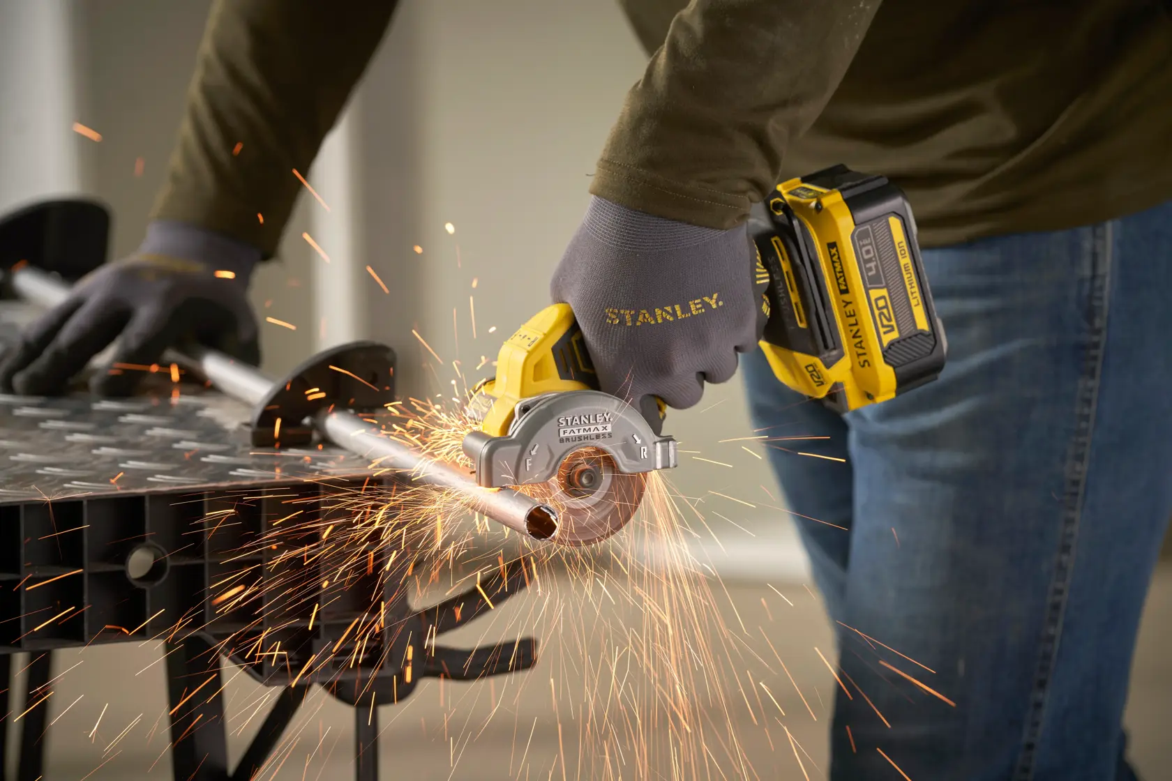 STANLEY SFMCM300B kompakte kabellose Kreissäge schneidet Metallrohr mit Funken, Nahaufnahme.
