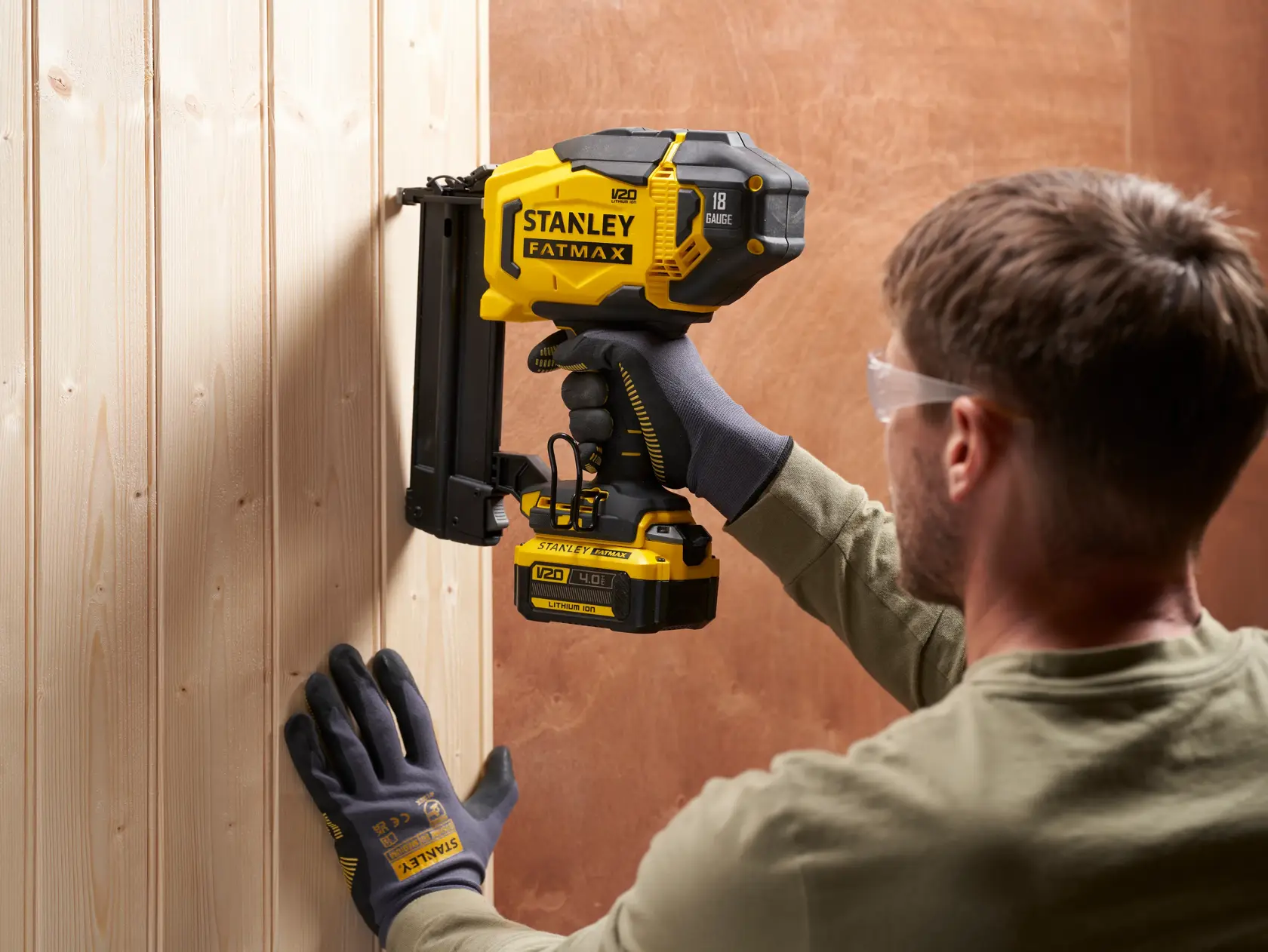 STANLEY SFMCN618B-XJ Akku-Nagler auf Holzplatte, Seitenansicht, gelb und schwarz.