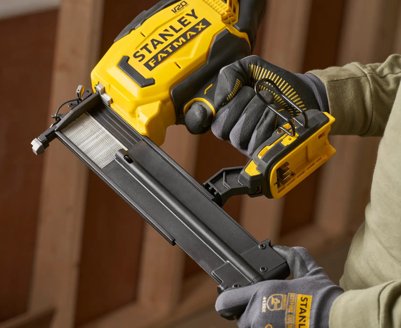 Foto des STANLEY SFMCN618B-XJ Akku-Naglers in Gelb und Schwarz, gehalten von behandschuhter Hand.