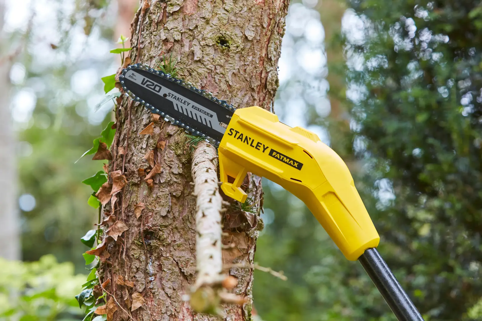 STANLEY SFMCPS620B Hochentaster schneidet Ast im Freien, gelber Körper und V20-Sägeblatt sichtbar.