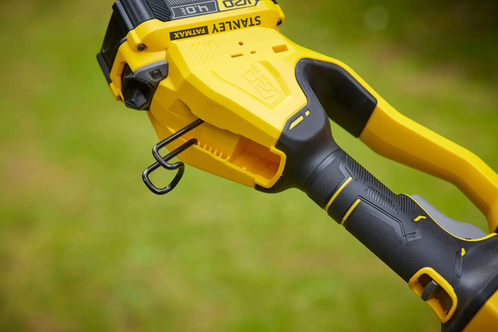 Nahaufnahme des Griffs des STANLEY SFMCPS620B Rasentrimmers mit gelb-schwarzem ergonomischem Griff und Haken.