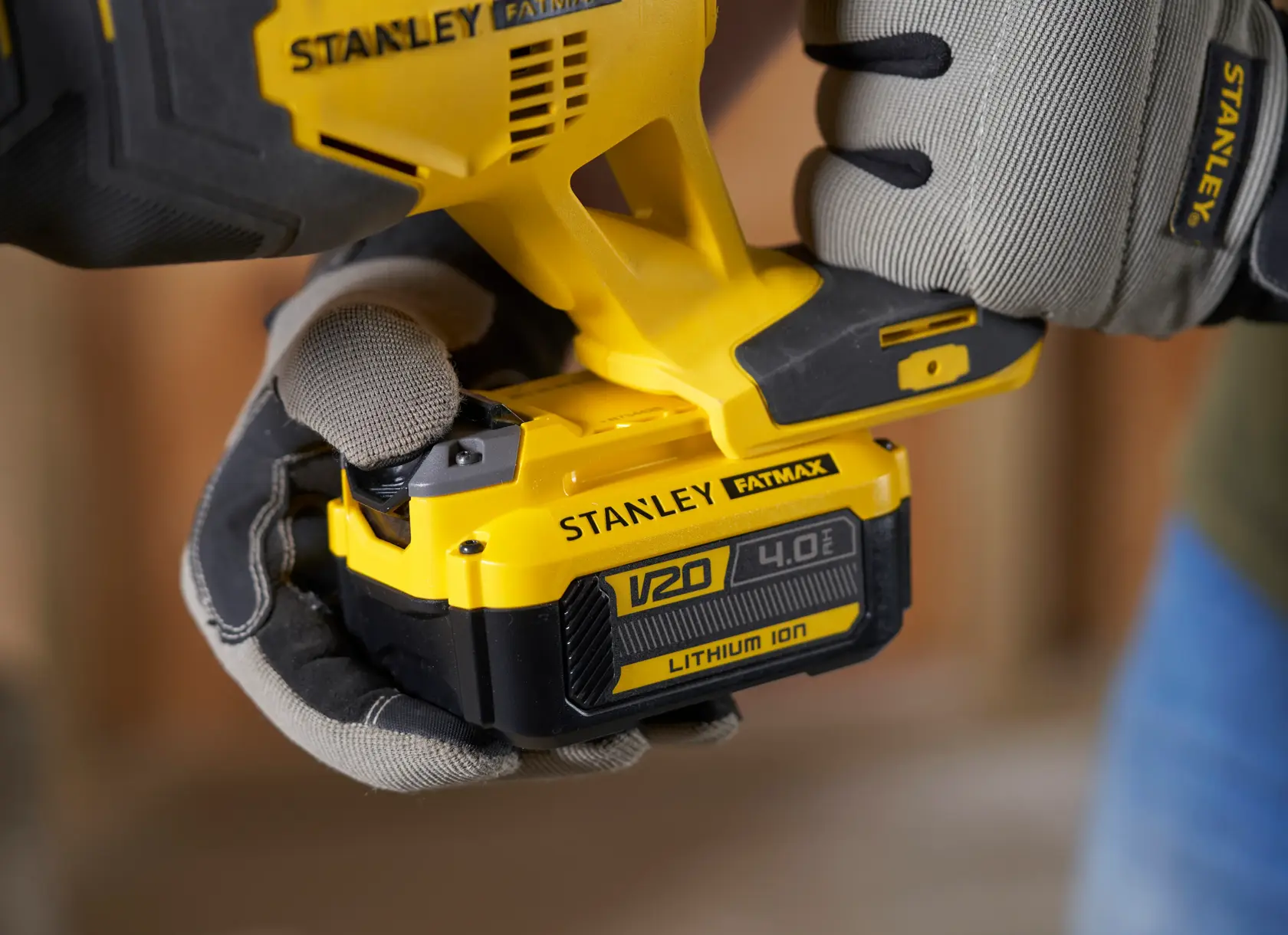 Foto des STANLEY SFMCS300B Elektrowerkzeugs mit V20 4.0Ah Lithium-Ionen-Akku in behandschuhten Händen.