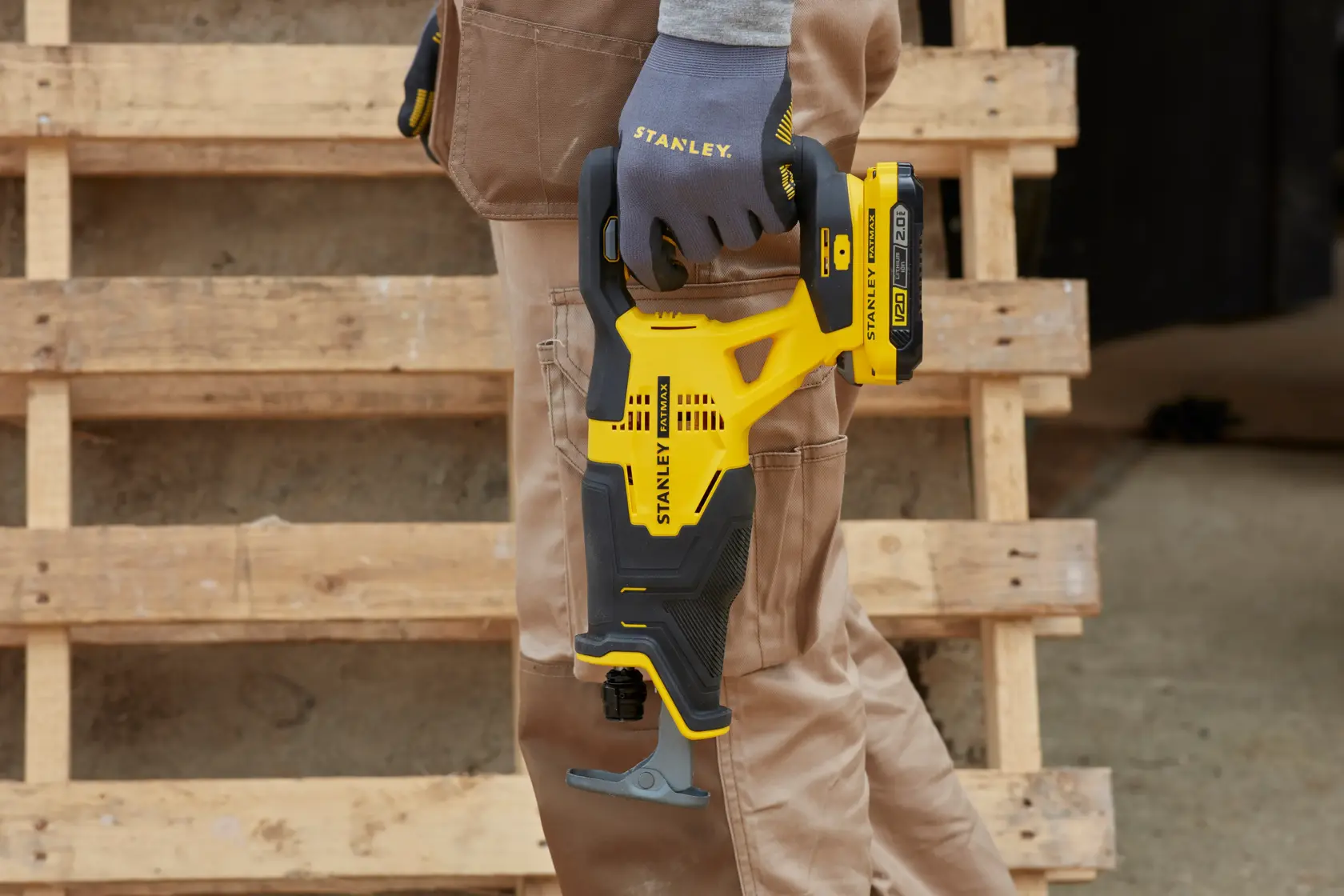 STANLEY SFMCS300D2K kabellose Säbelsäge, gelb-schwarzes Design, von einer behandschuhten Hand gehalten, im Freien.