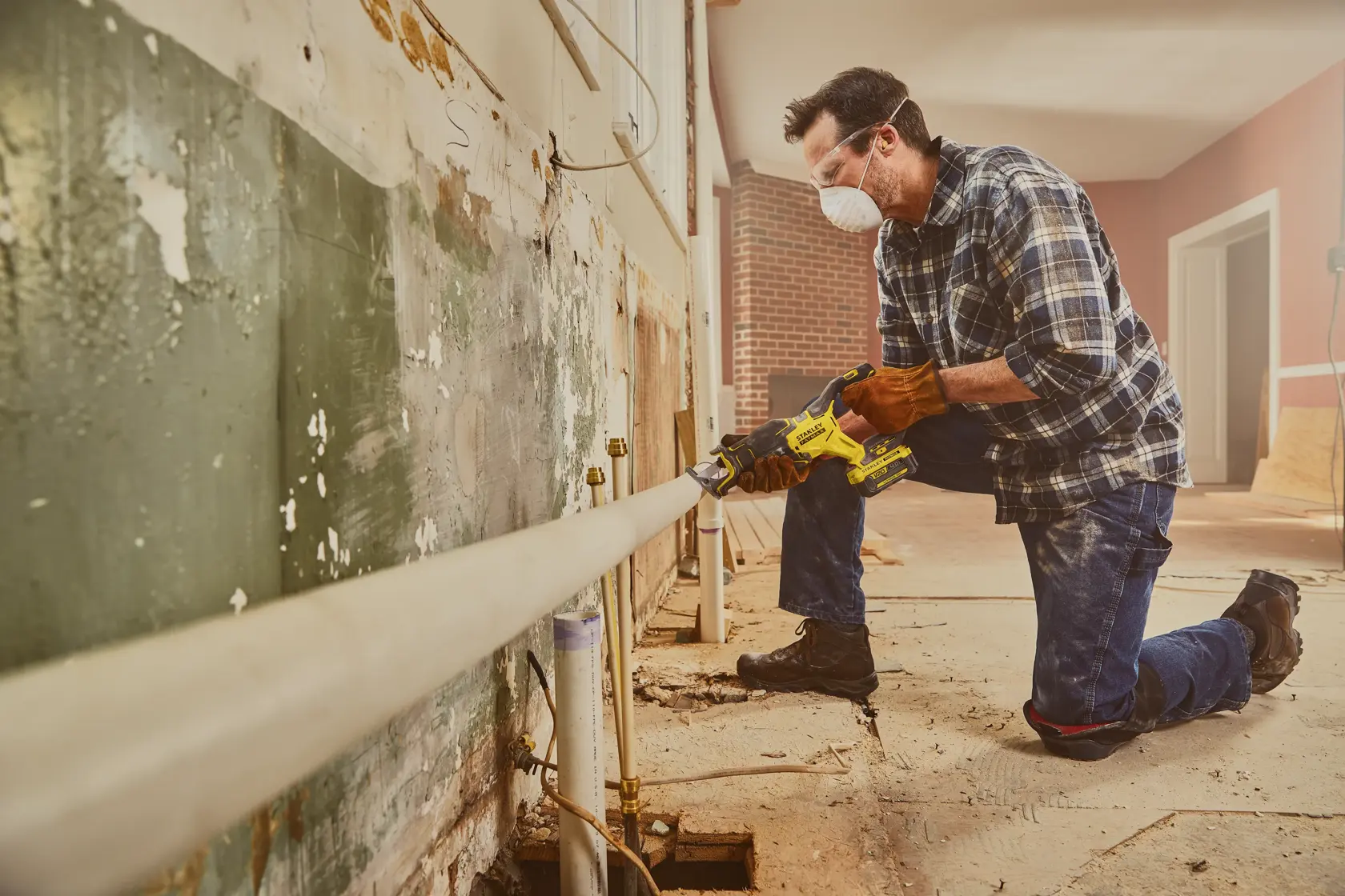 STANLEY SFMCS310B Säbelsäge von einem Arbeiter zum Schneiden eines Rohrs bei Renovierung verwendet.