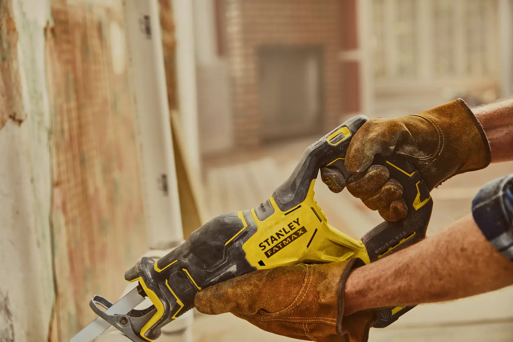 STANLEY SFMCS310B Säbelsäge mit gelb-schwarzem Gehäuse im Einsatz, Arbeitshandschuhe sichtbar.