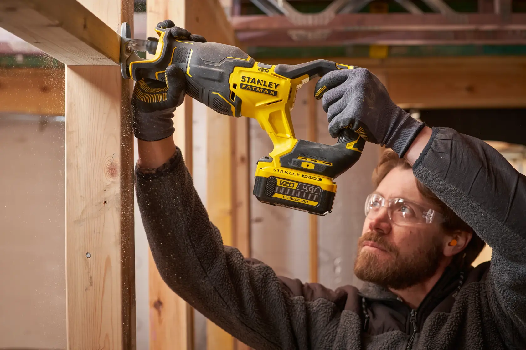 Foto der kabellosen STANLEY SFMCS311B-XJ Säbelsäge, die Holz sägt, gehalten von einer Person mit Handschuhen.