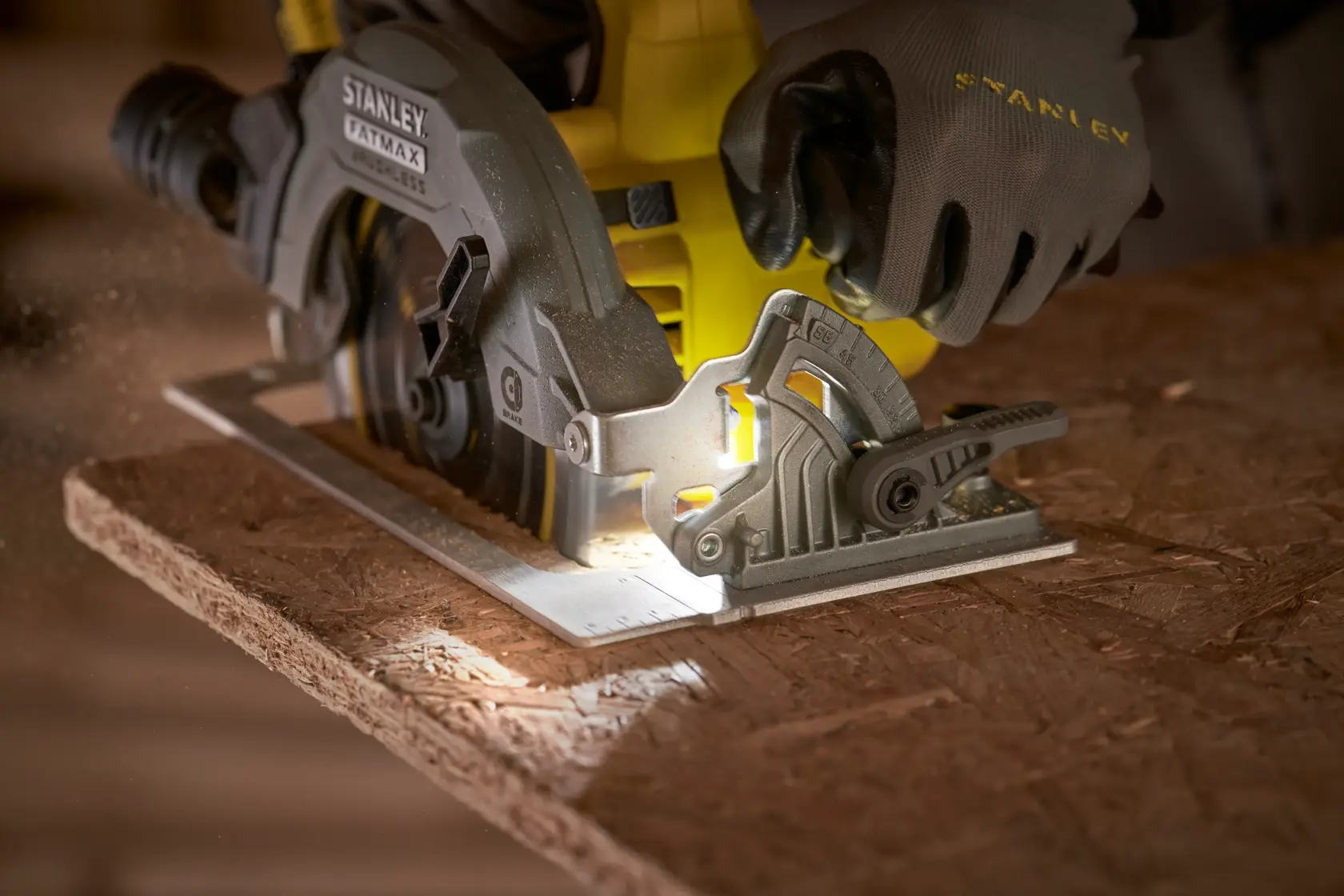 STANLEY SFMCS550B Kreissäge schneidet Holz, Nahaufnahme mit behandschuhter Hand am Gerät.