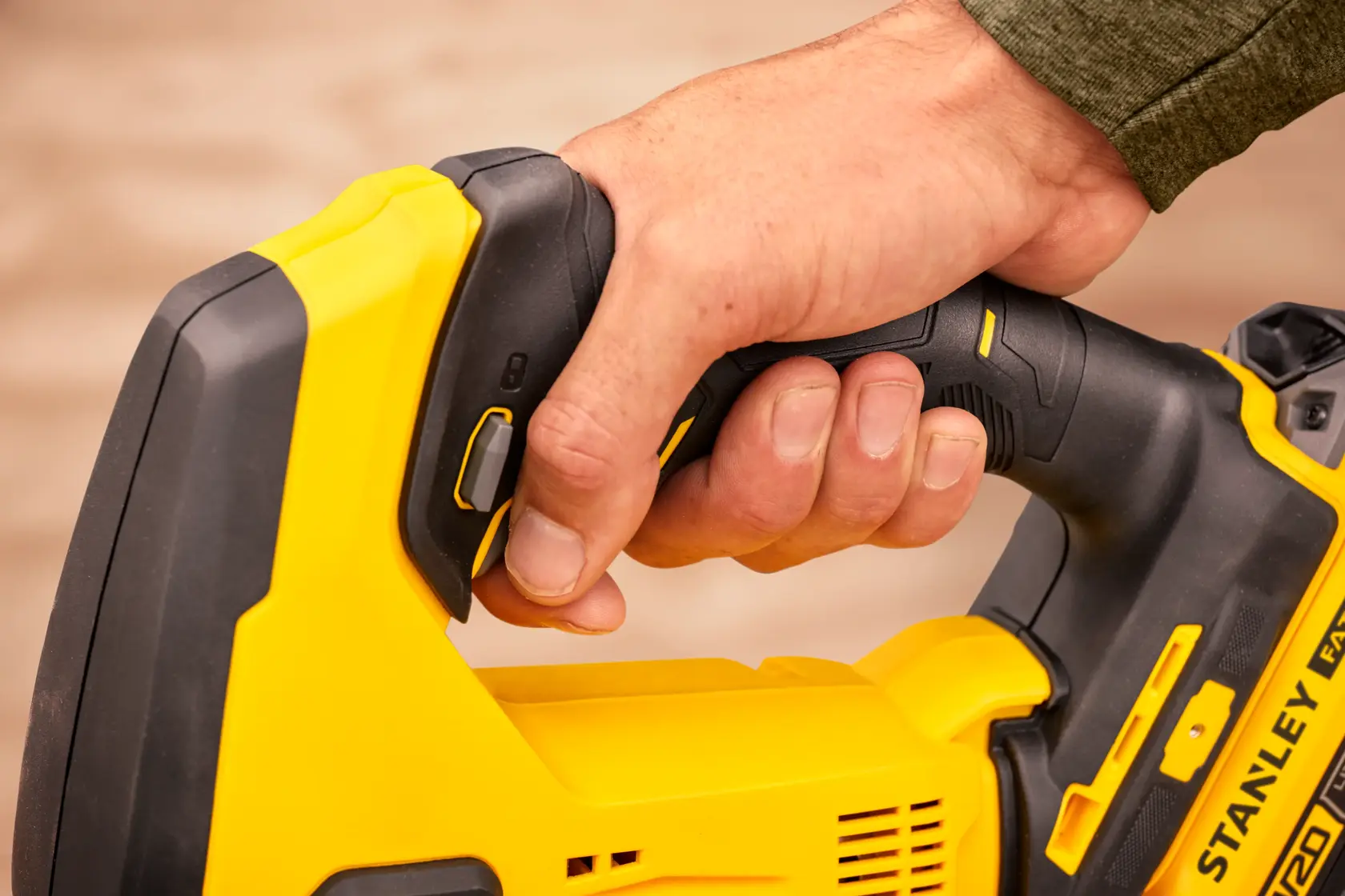 Foto einer Hand am Griff der STANLEY SFMCS600B Akku-Säge, Nahaufnahme des schwarz-gelben Werkzeugs.
