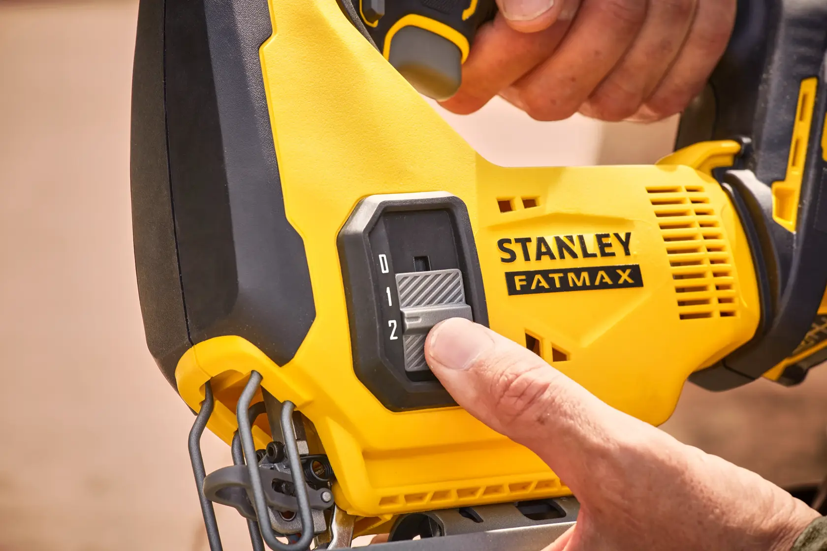 Foto vom Einstellen des Geschwindigkeitsreglers der STANLEY SFMCS600M2K Stichsäge, gelb-schwarzes Werkzeug Nahaufnahme.