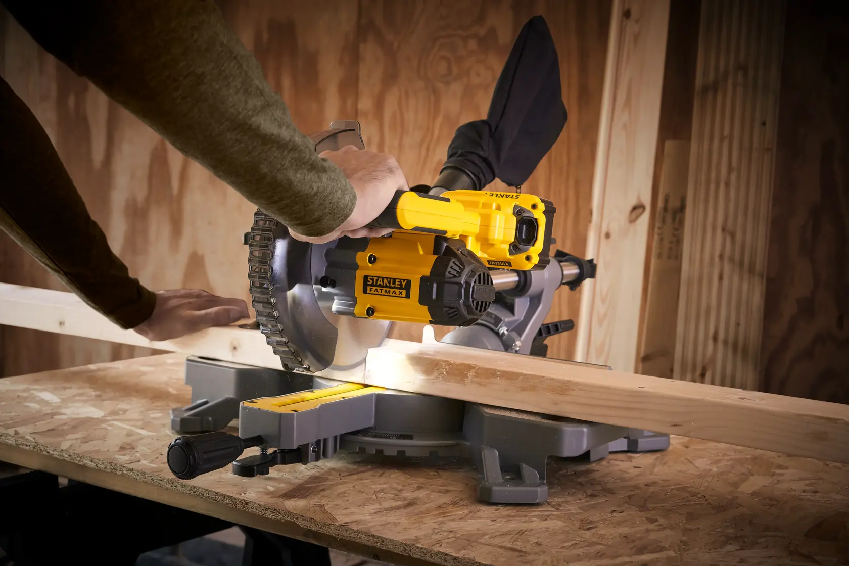 STANLEY SFMCS701M1 Gehrungssäge im Einsatz, schneidet Holz, Werkstattumgebung, Seitenansicht.
