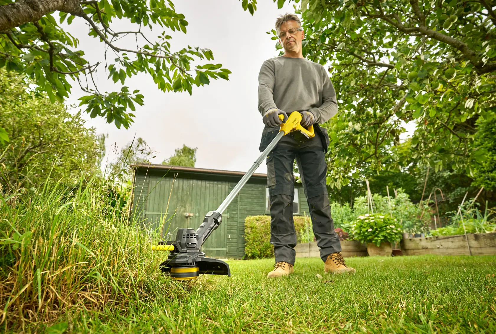 STANLEY SFMCST925B Rasentrimmer im Einsatz, Person schneidet Gras im Garten.