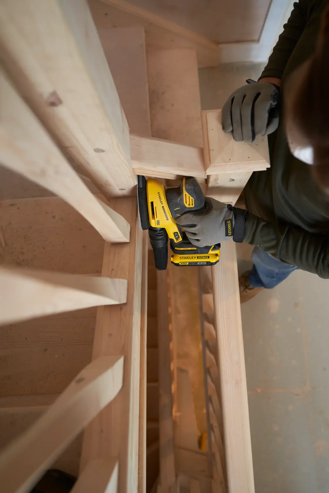 STANLEY SFMCW221D1S kabelloser Schleifer im Einsatz an Holztreppe, Nahaufnahme des Werkzeugs.