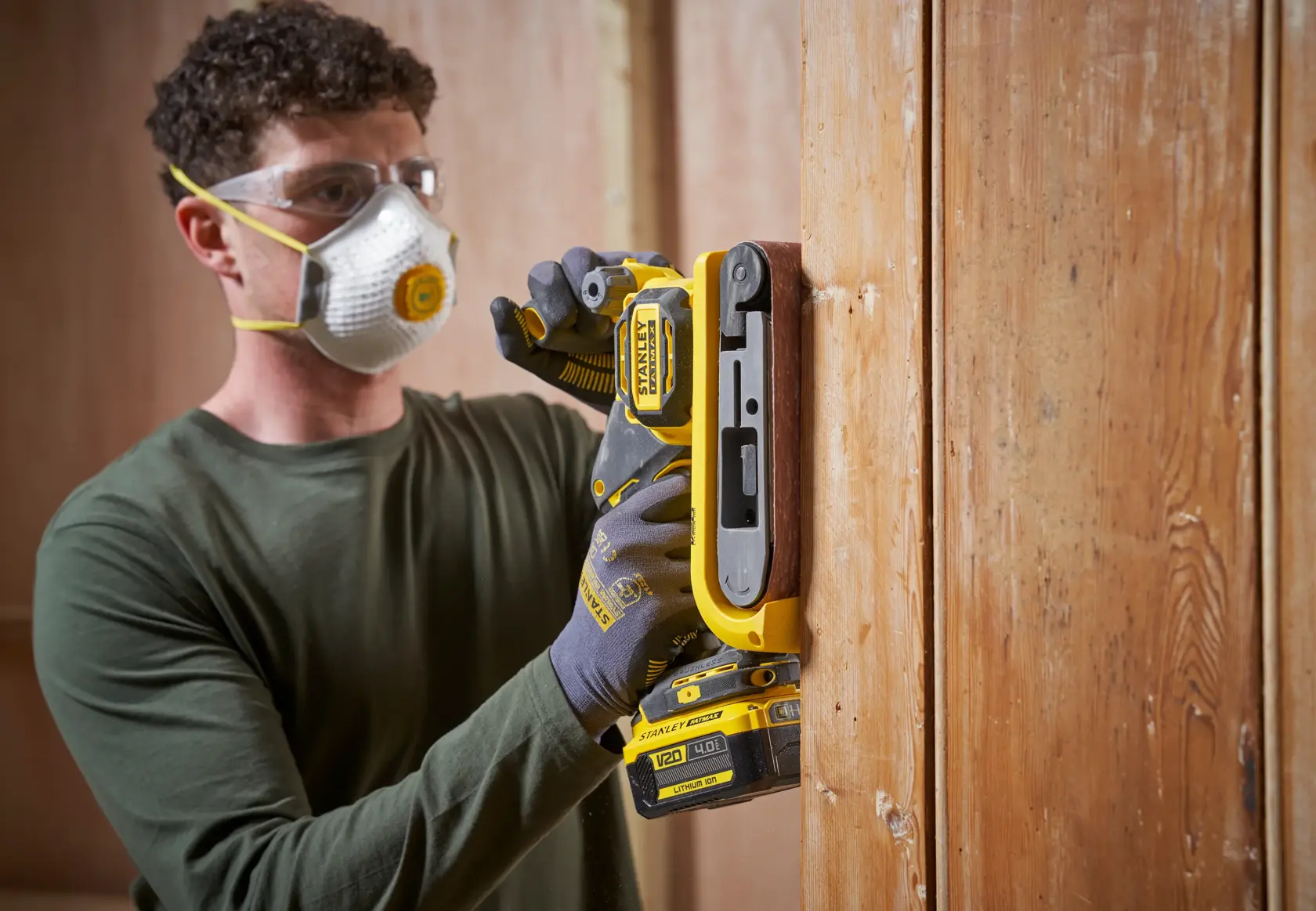 STANLEY SFMCW223B-XJ Akku-Schleifer bei Anwendung auf einer vertikalen Holzfläche, Nahaufnahme.