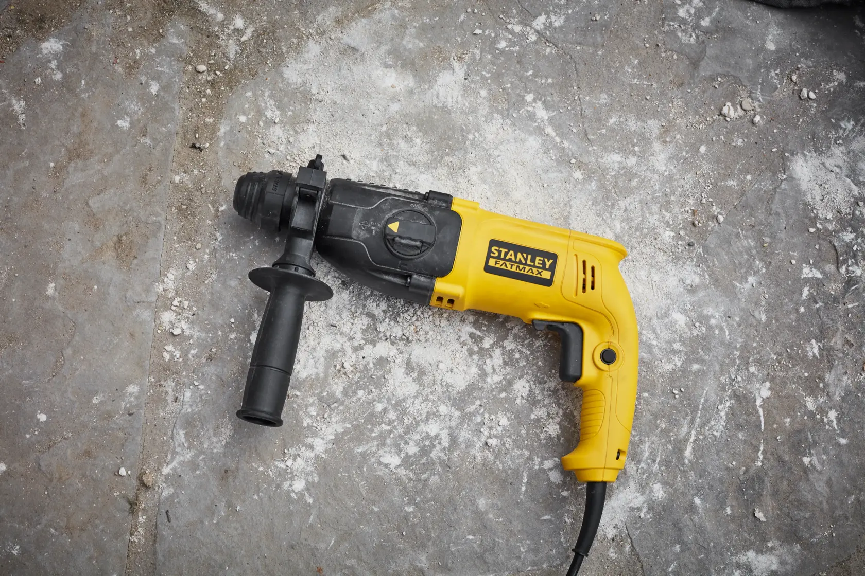 STANLEY SFMEH200K gelber und schwarzer kabelgebundener Bohrhammer mit Seitengriff auf Beton.