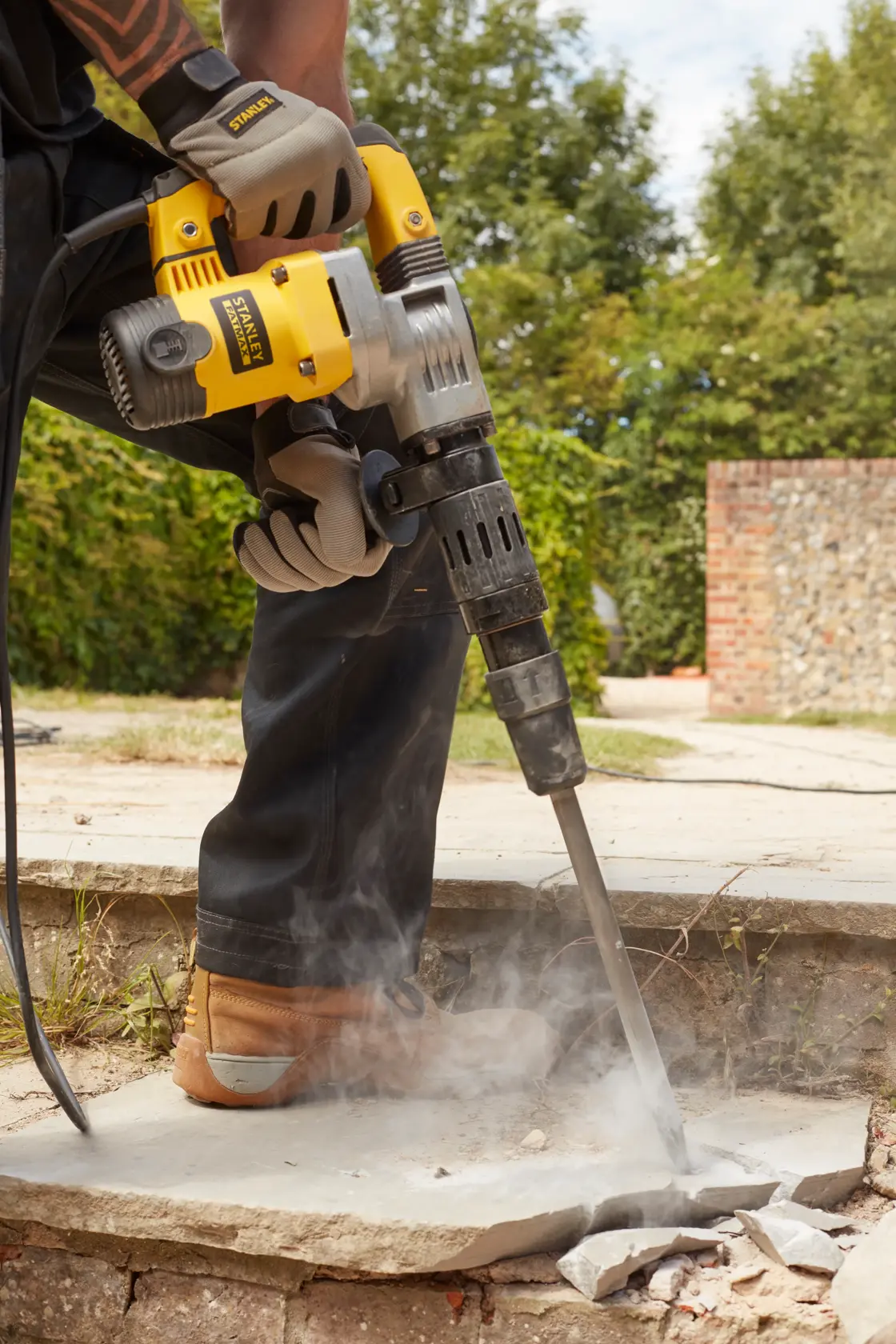 STANLEY SFMEH220K-QS Bohrhammer bricht Beton im Freien, Nahaufnahme des Werkzeugs im Einsatz.