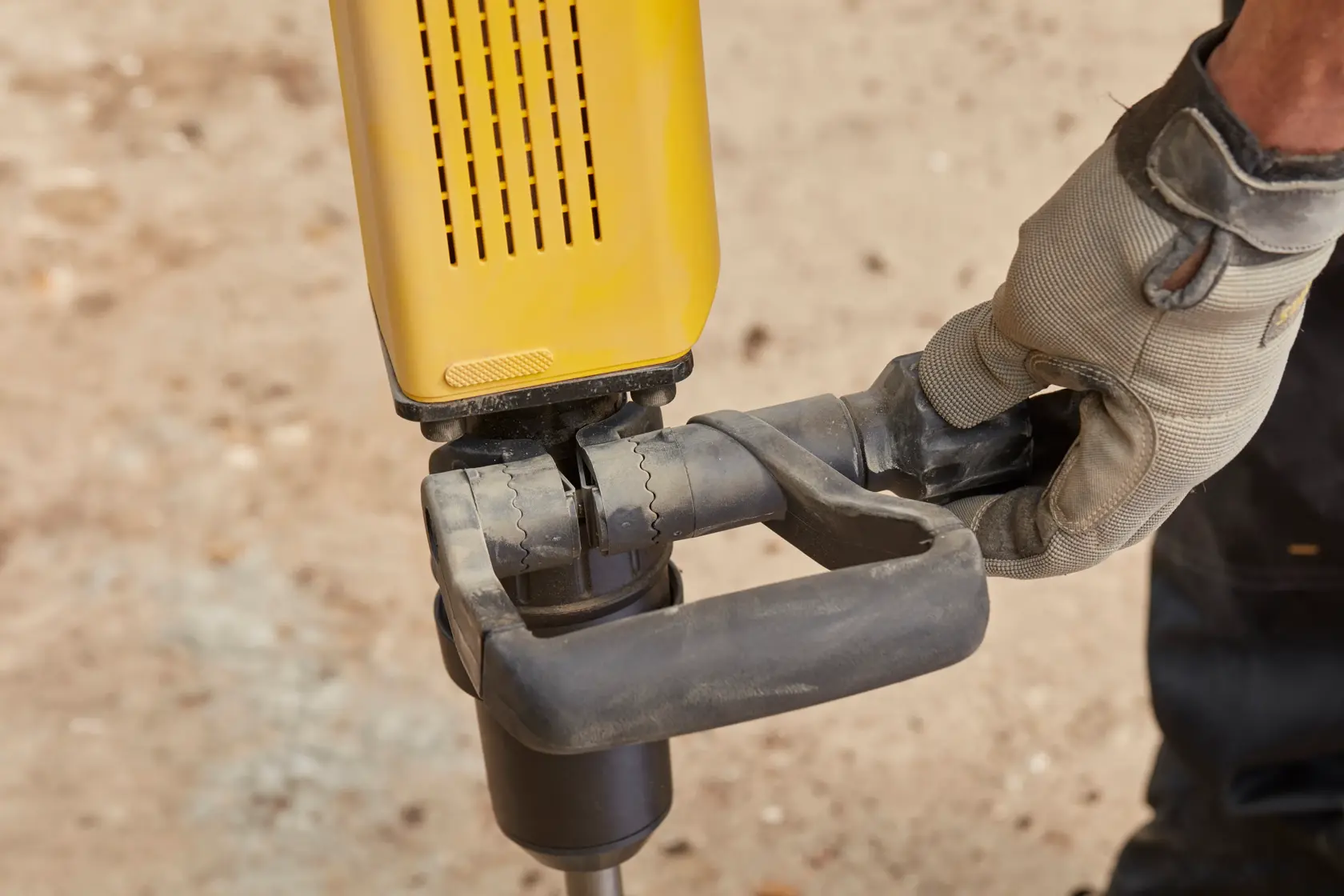 Foto des STANLEY SFMEH230K-QS Bohrhammer-Griffs, gehalten von einer behandschuhte Hand, Nahaufnahme draußen.