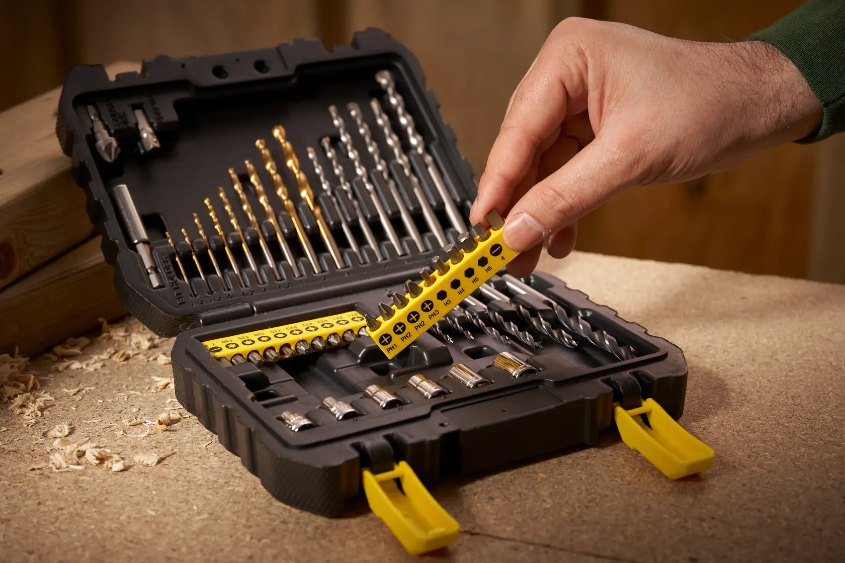 STANLEY STA88546 Bohr- und Bitset-Koffer geöffnet auf Werkbank, Hand wählt Bitleiste.