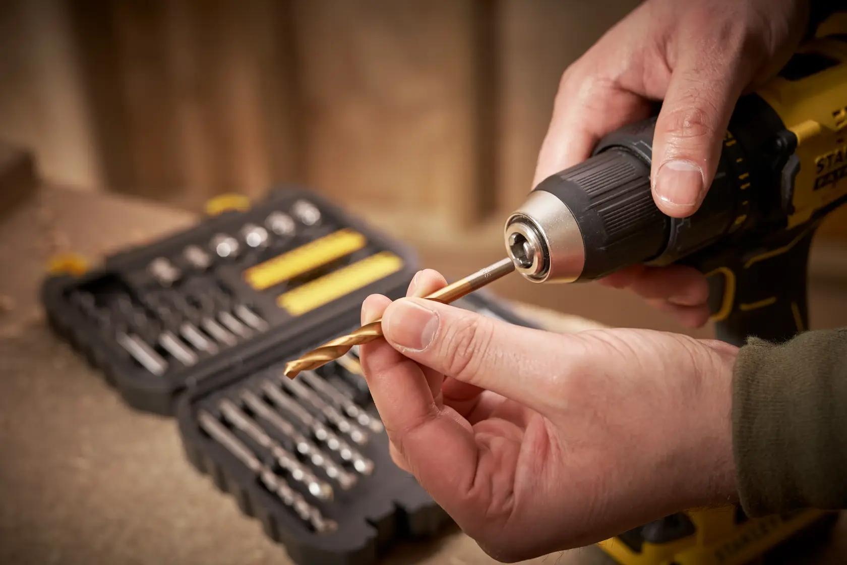 STANLEY STA88546 Bohrer-Set, Person setzt Bohrer in gelbe Bohrmaschine, Etui im Hintergrund sichtbar.