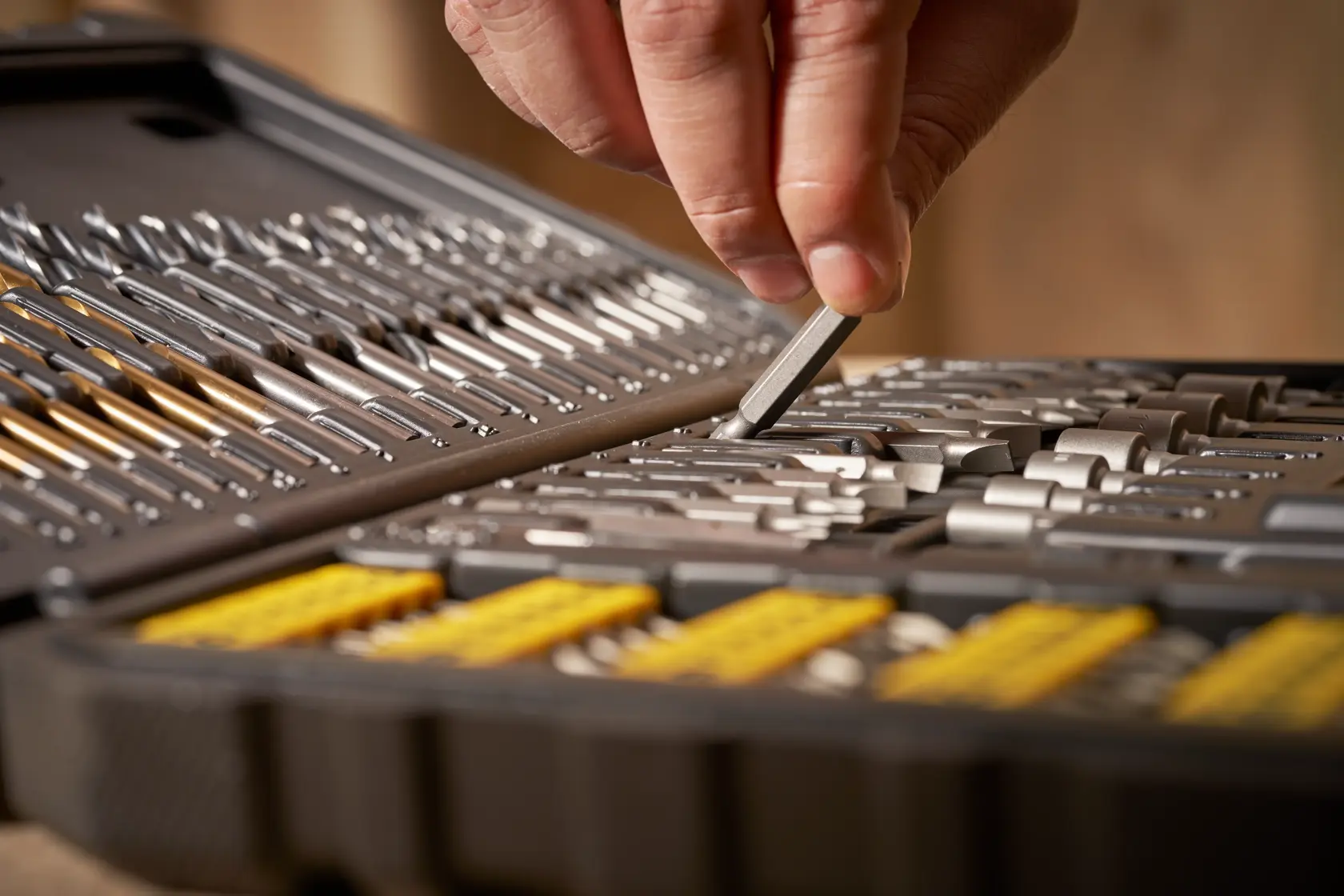 STANLEY STA88548 Bohrer- und Bit-Set im Koffer, Nahaufnahme: Hand wählt Bit aus Fächern.