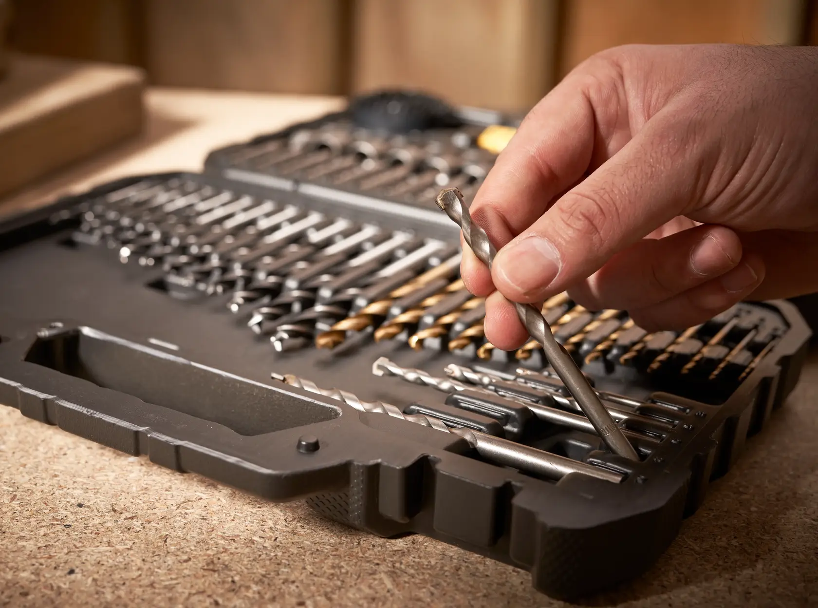 STANLEY STA88548 Bohrerset-Koffer mit Hand, die einen Bit auswählt, Nahaufnahme auf Werkbank.