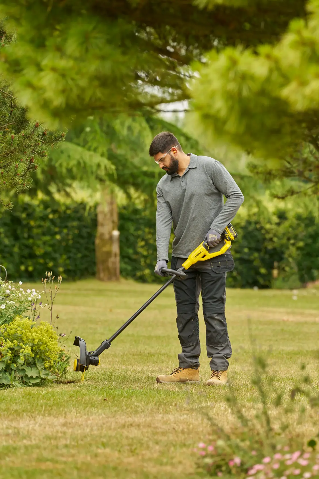 STANLEY STCST933M1 Rasentrimmer im Garten verwendet, gelb-schwarzes Design, akkubetrieben.