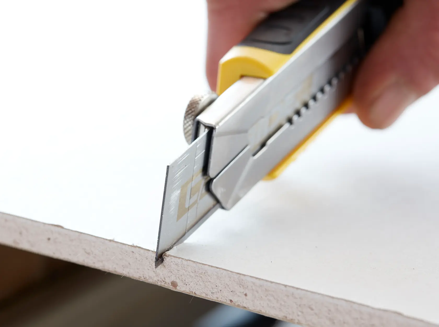 STANLEY STHT0-11825 Universalmesser schneidet Gipskarton, Nahaufnahme von Klinge und Griff.