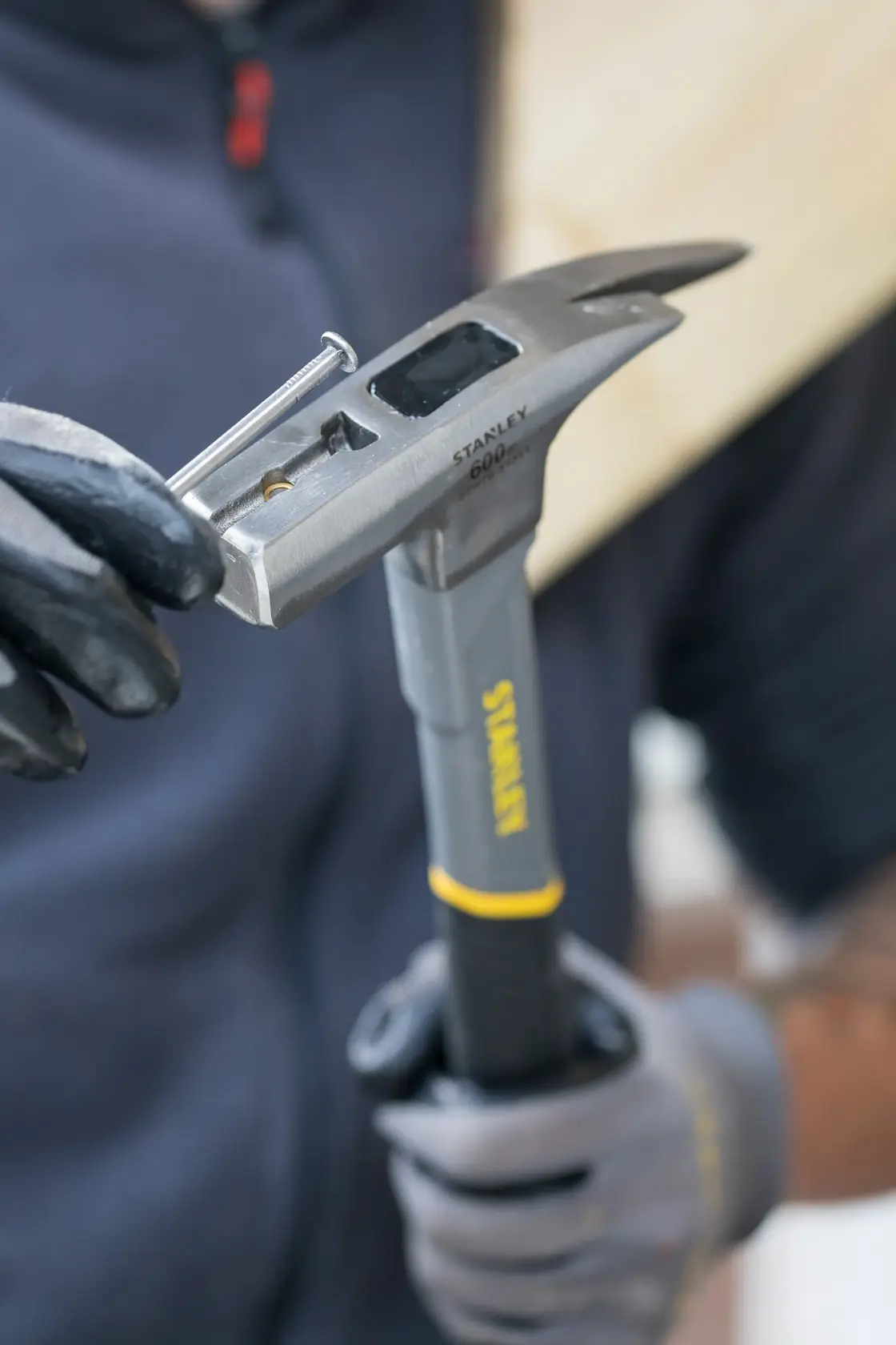 STANLEY STHT0-51311 Hammer mit Handschuhen gehalten, zeigt die Nagelstarterfunktion im Einsatz.
