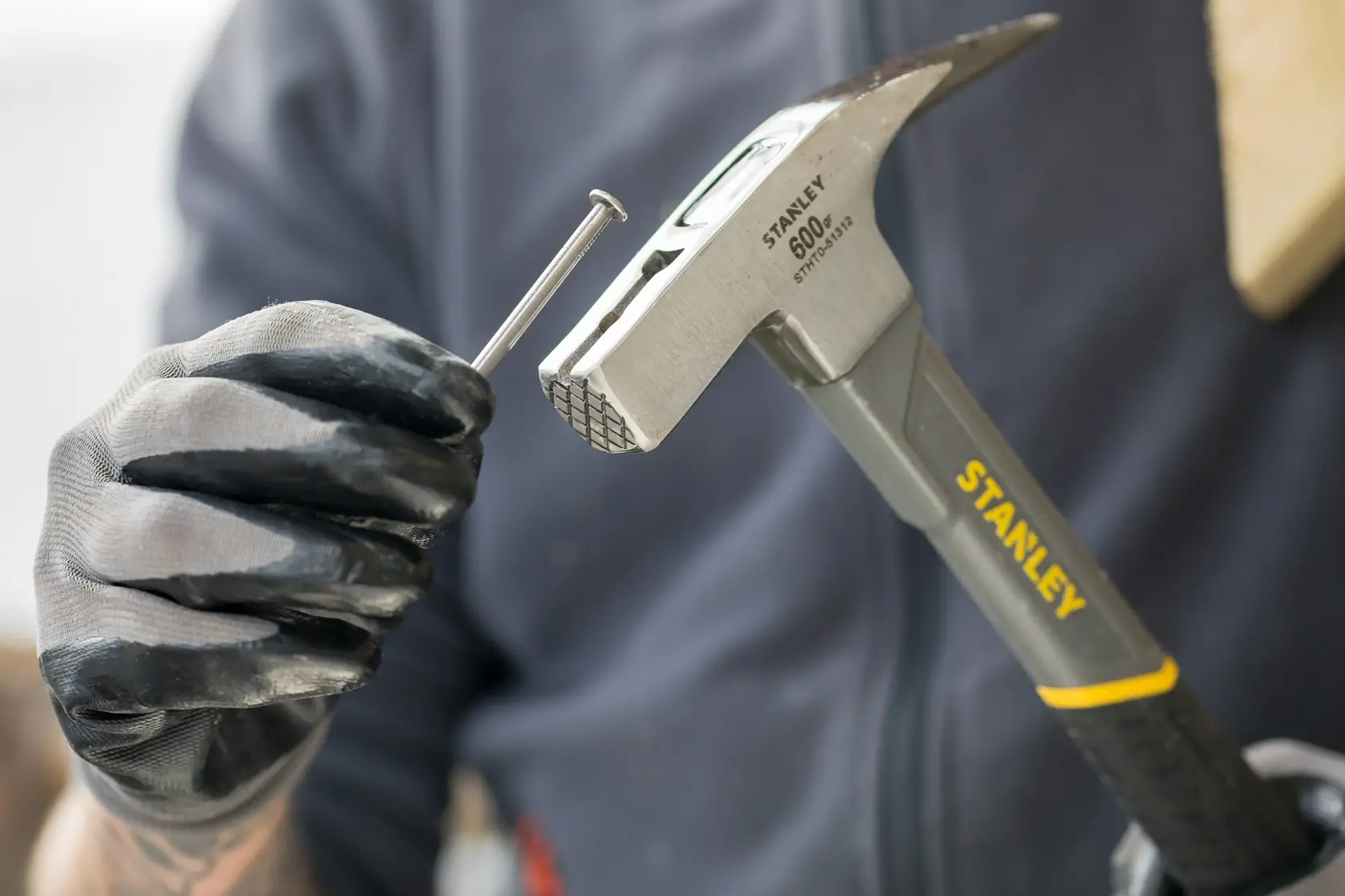 Stanley STHT0-51312 Hammer Nahaufnahme mit Handschuhhand und Nagel, Produktkategorie Fotografie.