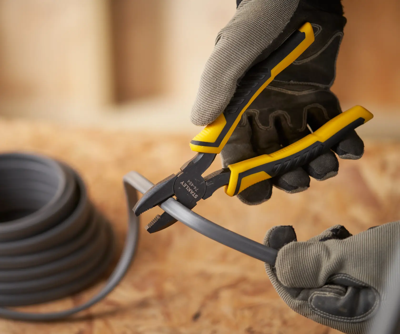 Foto der STANLEY STHT0-74367 Zange beim Schneiden von Kunststoffrohr, Arbeiter mit Handschuhen.