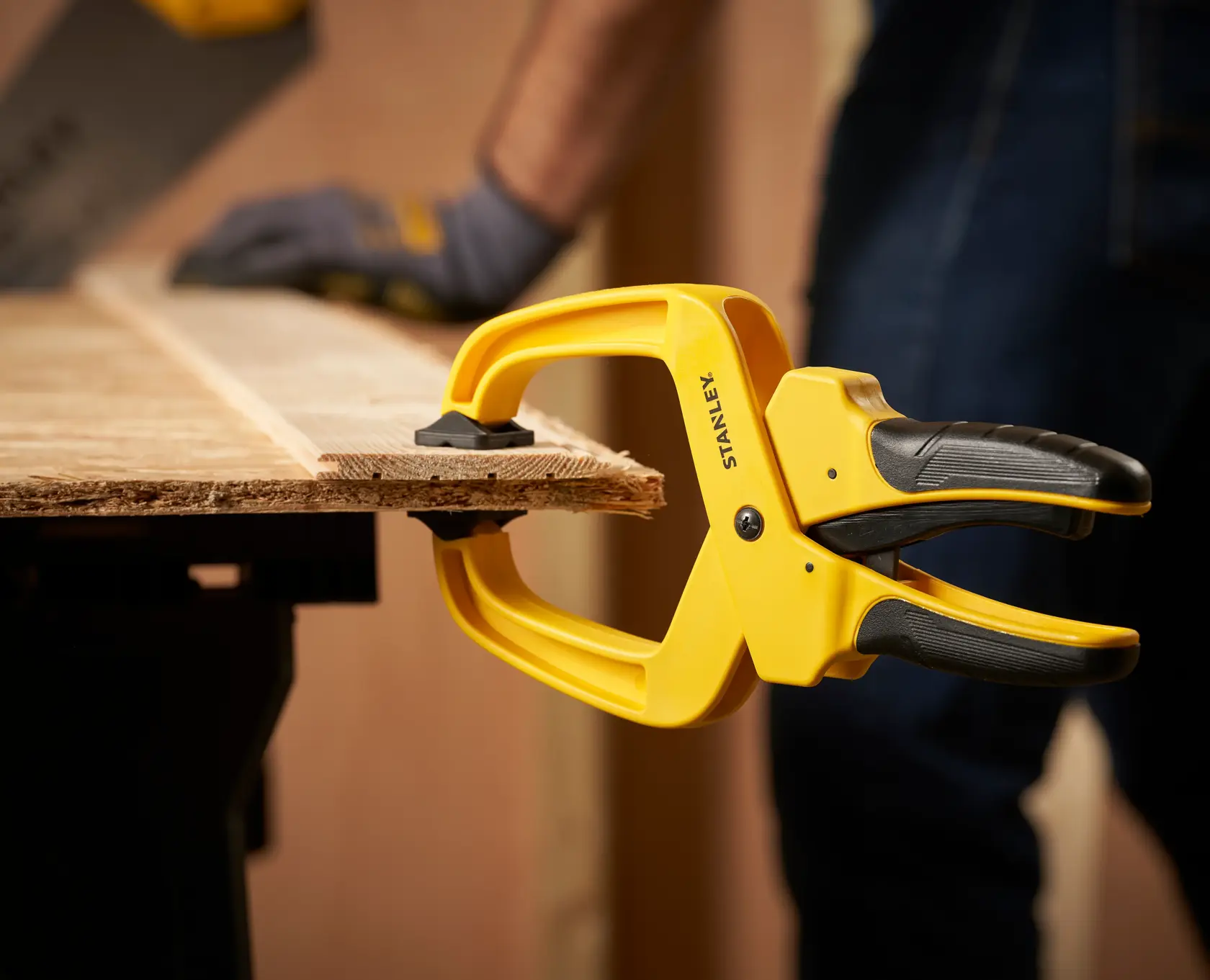 STANLEY STHT0-83200 Federzwinge hält Holz auf Werkbank, Nahaufnahme bei Holzarbeiten.