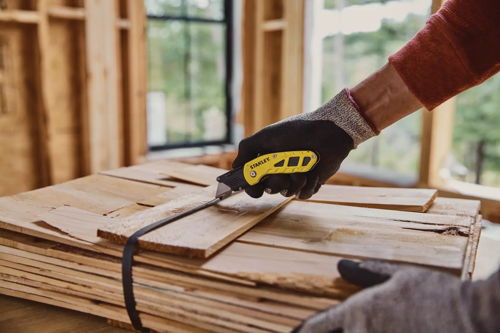 Foto von STANLEY STHT10424-0 Klapp-Universalmesser schneidet Holzriemen auf einer Baustelle.