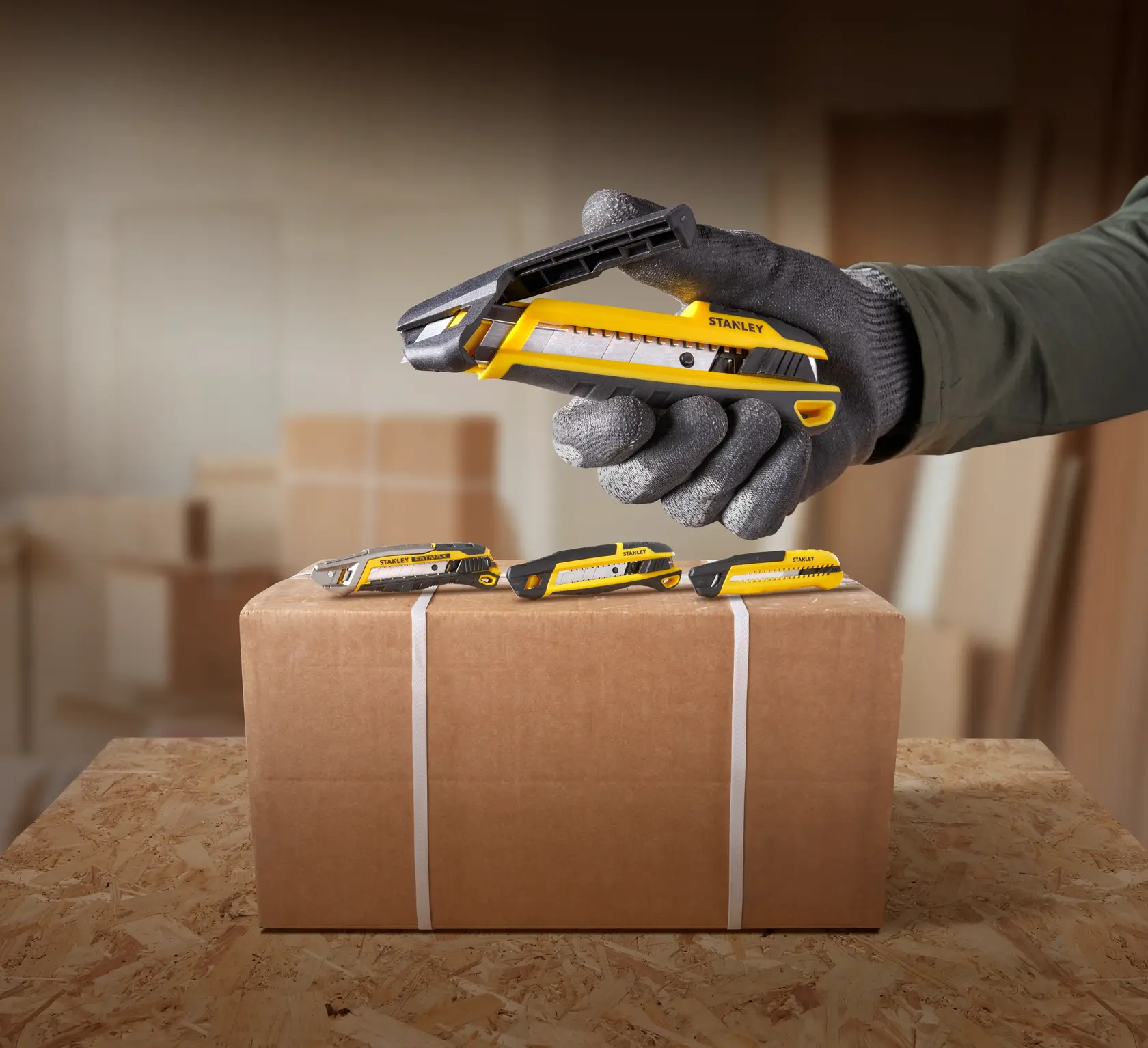 Foto des STANLEY STHT10501-0 gelb-schwarzen Cuttermessers, schneidet Karton mit drei Messern.
