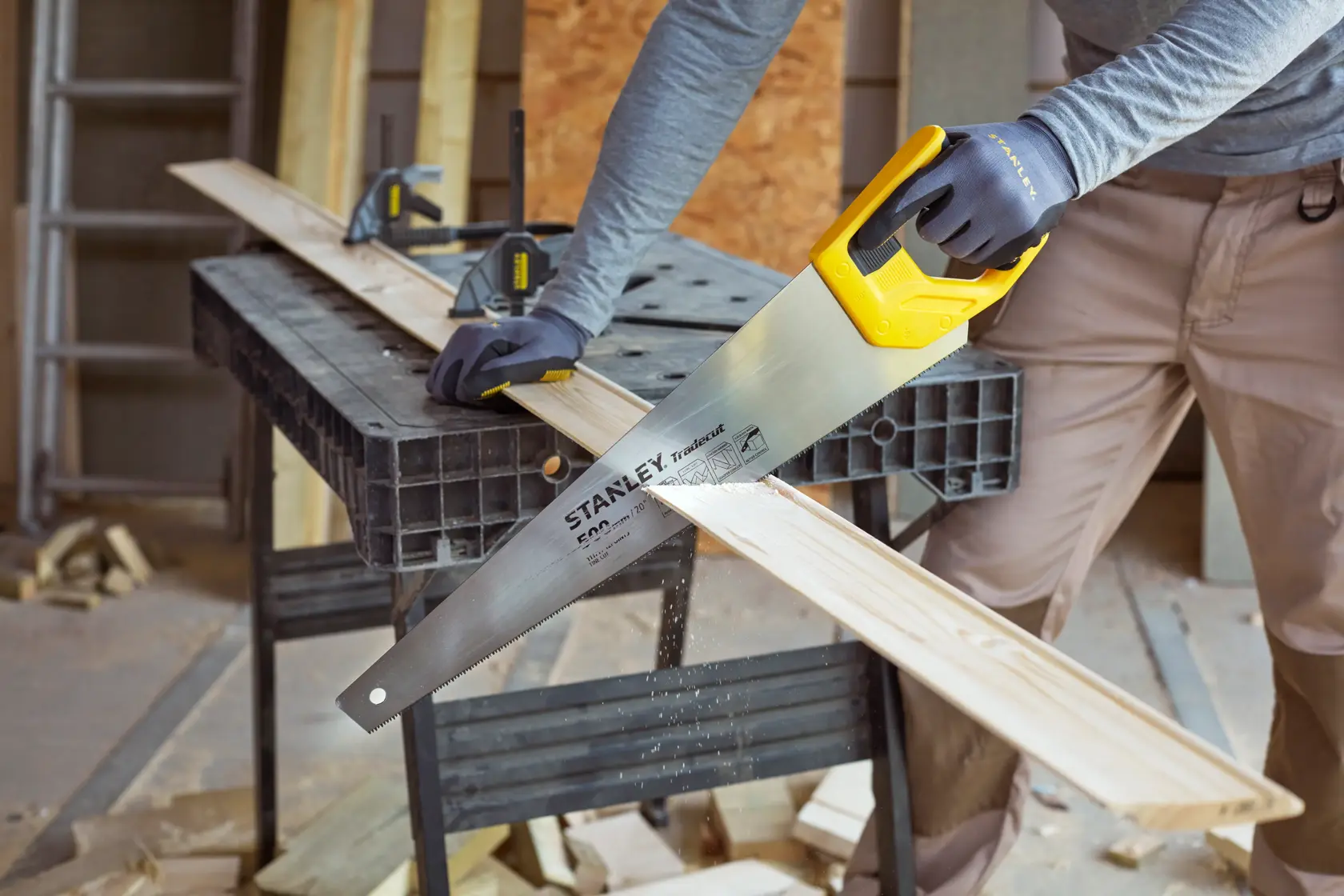 STANLEY STHT20350-1 Handsäge mit gelbem Griff schneidet Holzbrett in Werkstatt, Kategorie Fotografie.