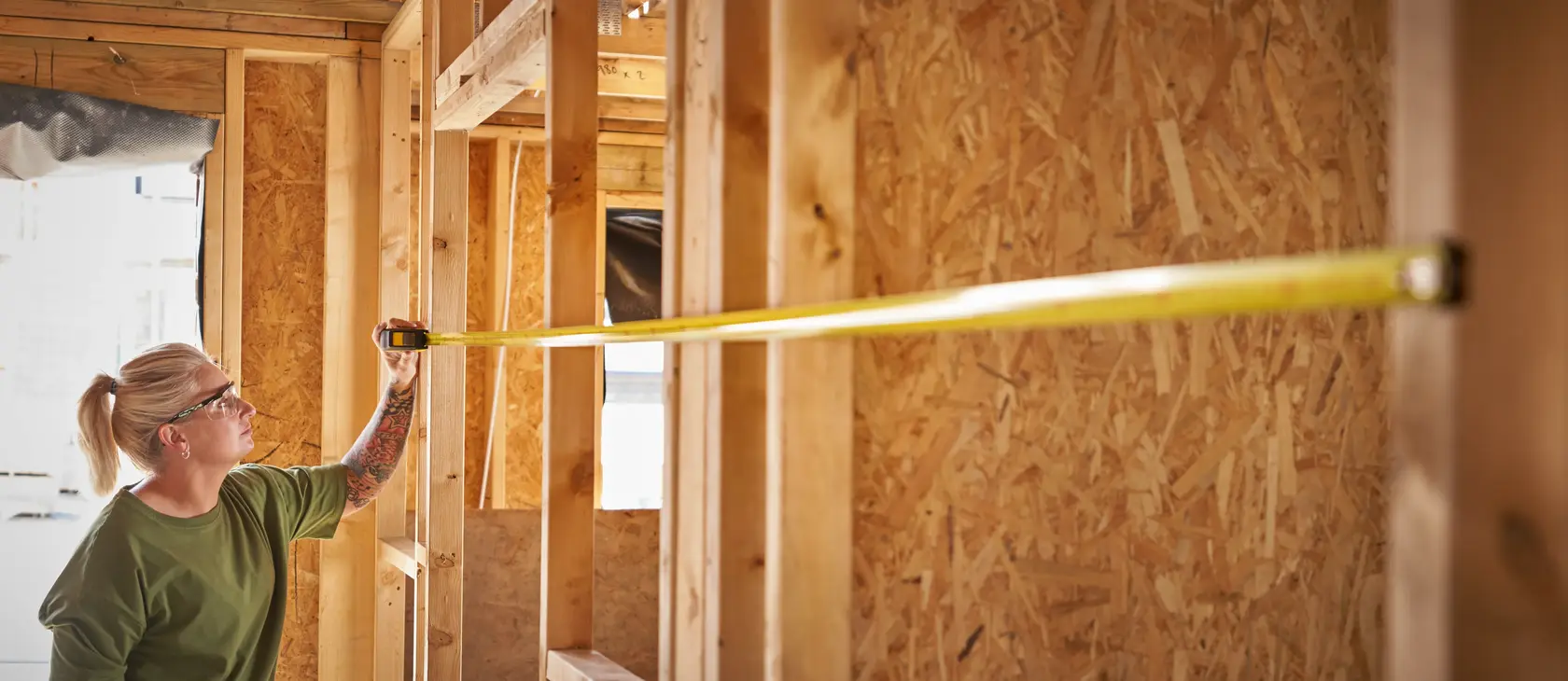 Person misst Wand mit STANLEY STHT37233-0 Maßband auf Baustelle.