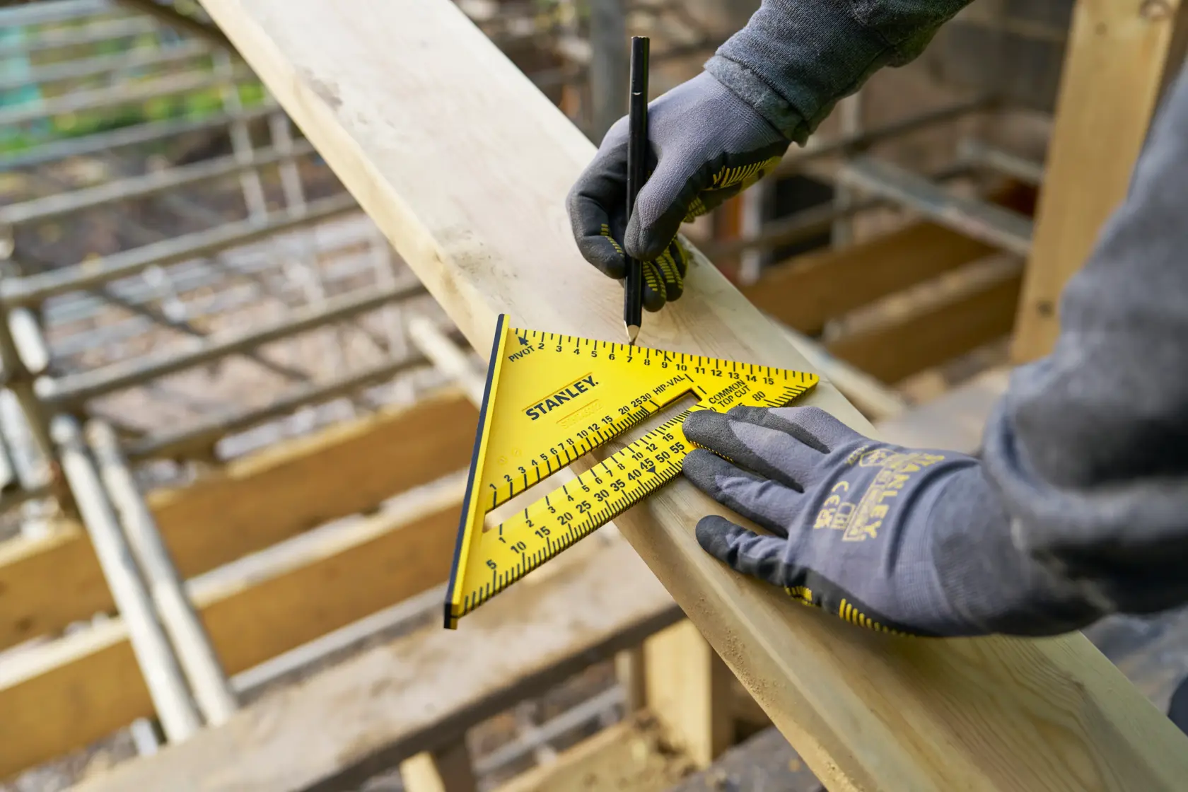 Foto des gelben STANLEY STHT46012-0 Zimmermannswinkels auf Holzbrett, Arbeiter markiert mit Bleistift, Baustelle.